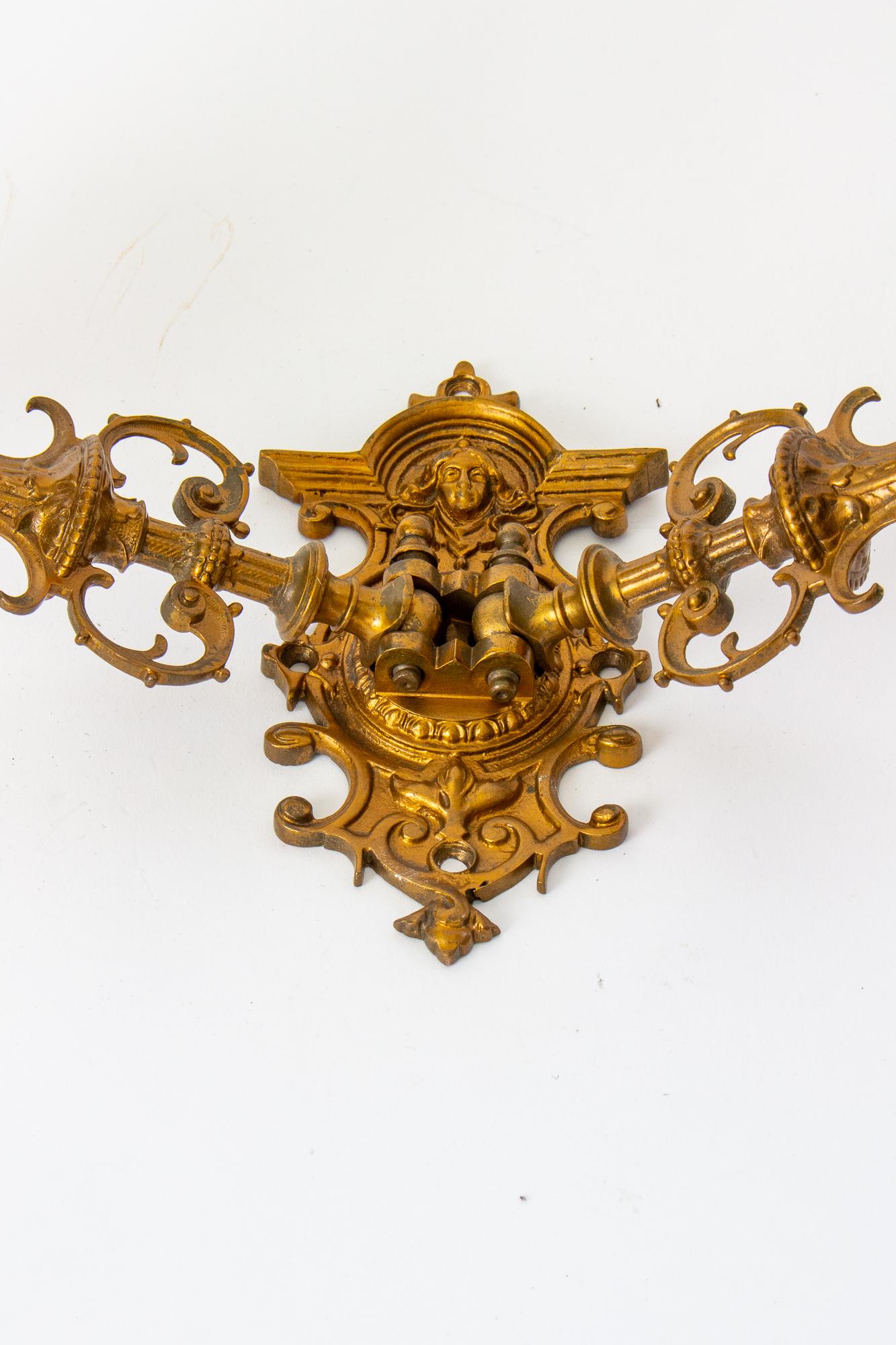 A pair of victorian swivel arm sconces. Gothic Revival style, with two arms. Onate throughout, the backplate features a womans face. Cast bronze, with an aged gilt finish. For candles. C. 1860.