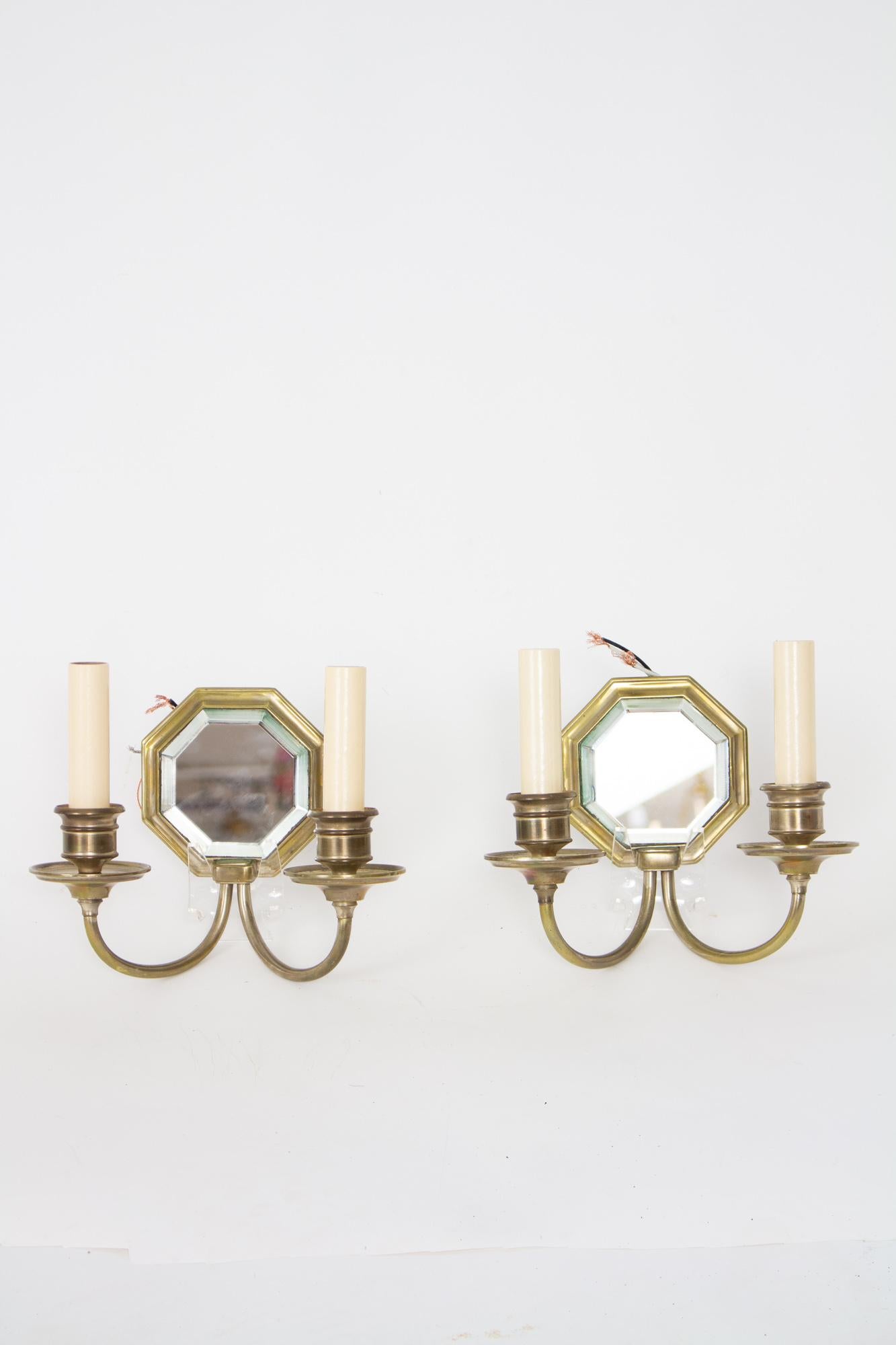 Classic two arm sconces with a worn nickel finish. Unmarked but of the same quality of E.F. Caldwell pieces of the same era. Octagonal mirror backs. Rewired with new candlecovers for use in the US 120 V. Complete and ready to install. American, C.