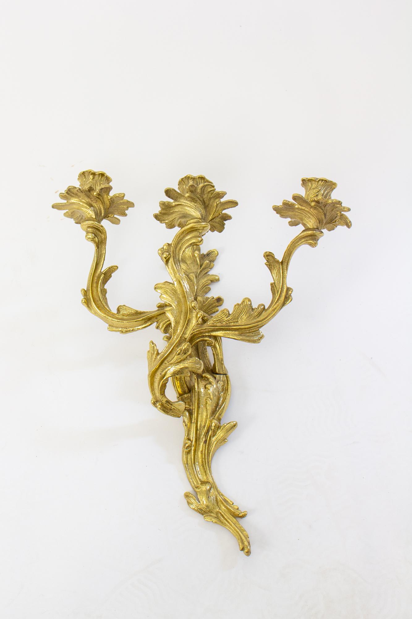 Mid 20th Century brass Louis XV style sconces - a pair. Solid cast brass wall sconces with three arms in an orate and organic manner characteristic of rococo style. By Glo-Mar of NYC.