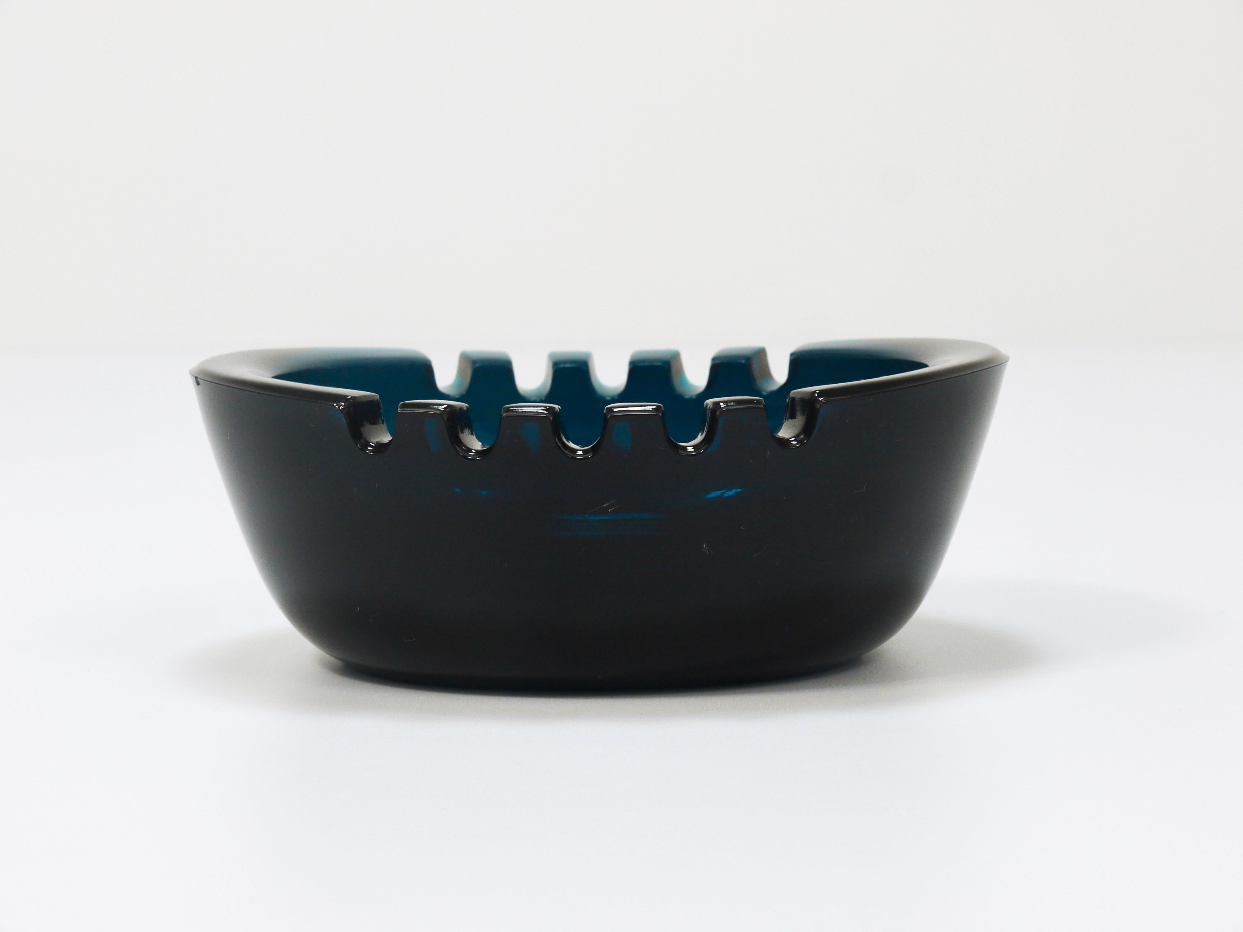 A beautiful midcentury glass ashtray, model Stadion, designed by the Finnish designer Saara Hopea in 1959. Executed by Nuutajärvi Notsjö, Finland. Made of solid green blue glass. In very good condition, probably unused. 
To  follow us please click