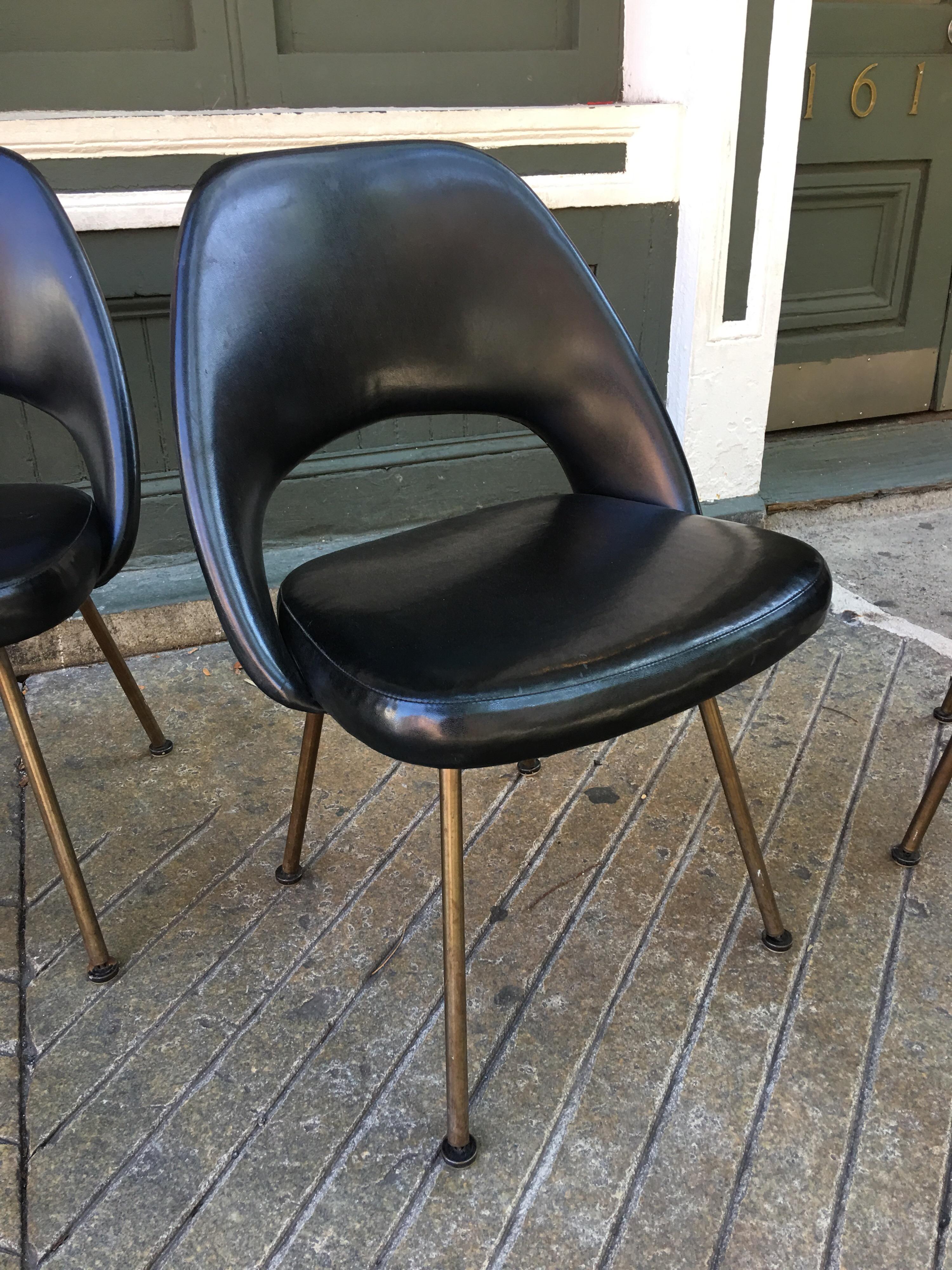 Saarinen for Knoll set of 4 black vinyl chairs with rare original bronze finish legs. Offered originally for a short time in the 1960s legs have a brownish finish. Black vinyl is the original and shows some wear, including a couple pictured slits in