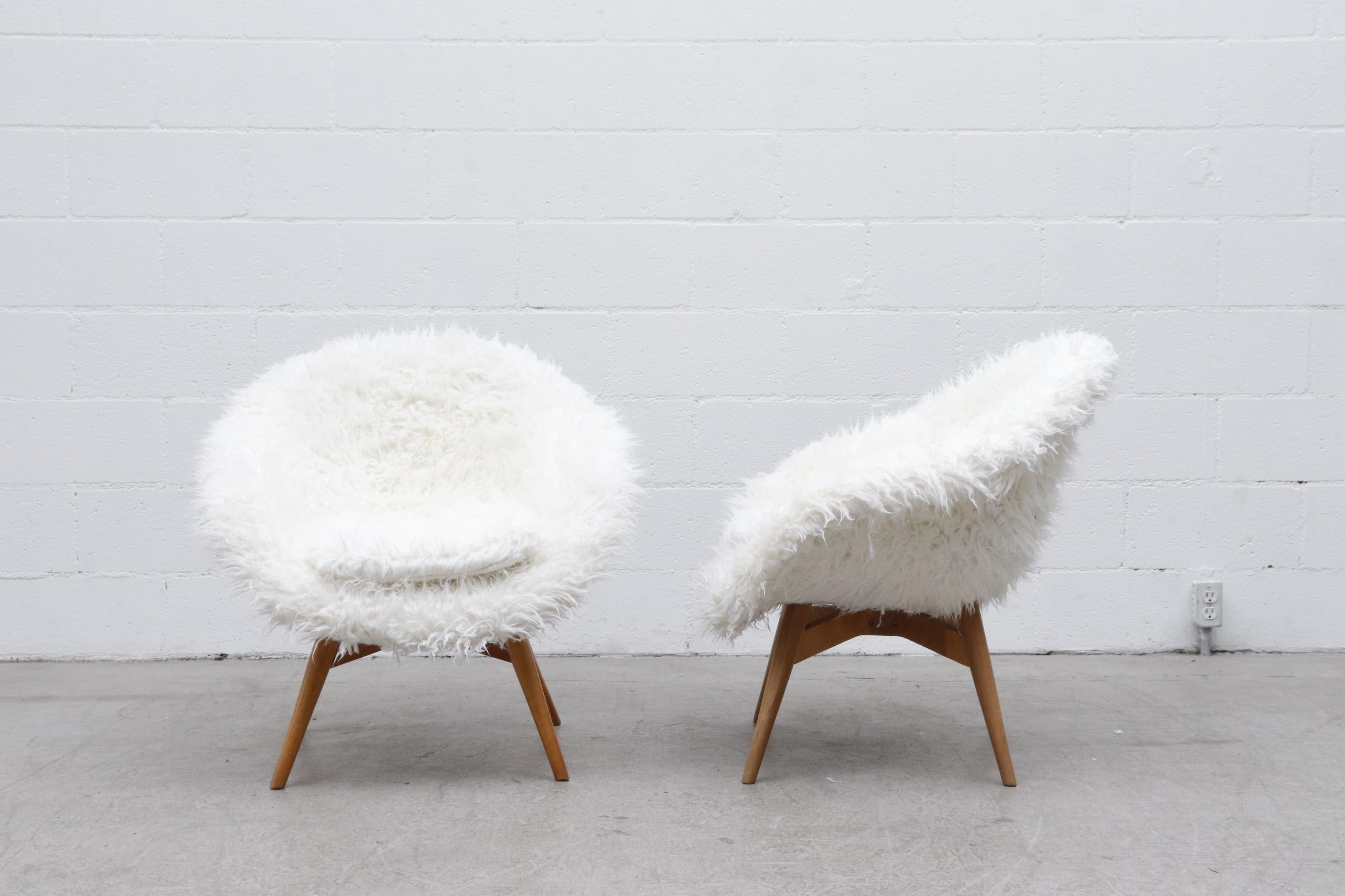 Midcentury Saarinen style bucket lounge chairs with new white faux fur upholstery and original tapered wood legs. Frame in original condition with wear and patina consistent with their age and use. Priced individually.