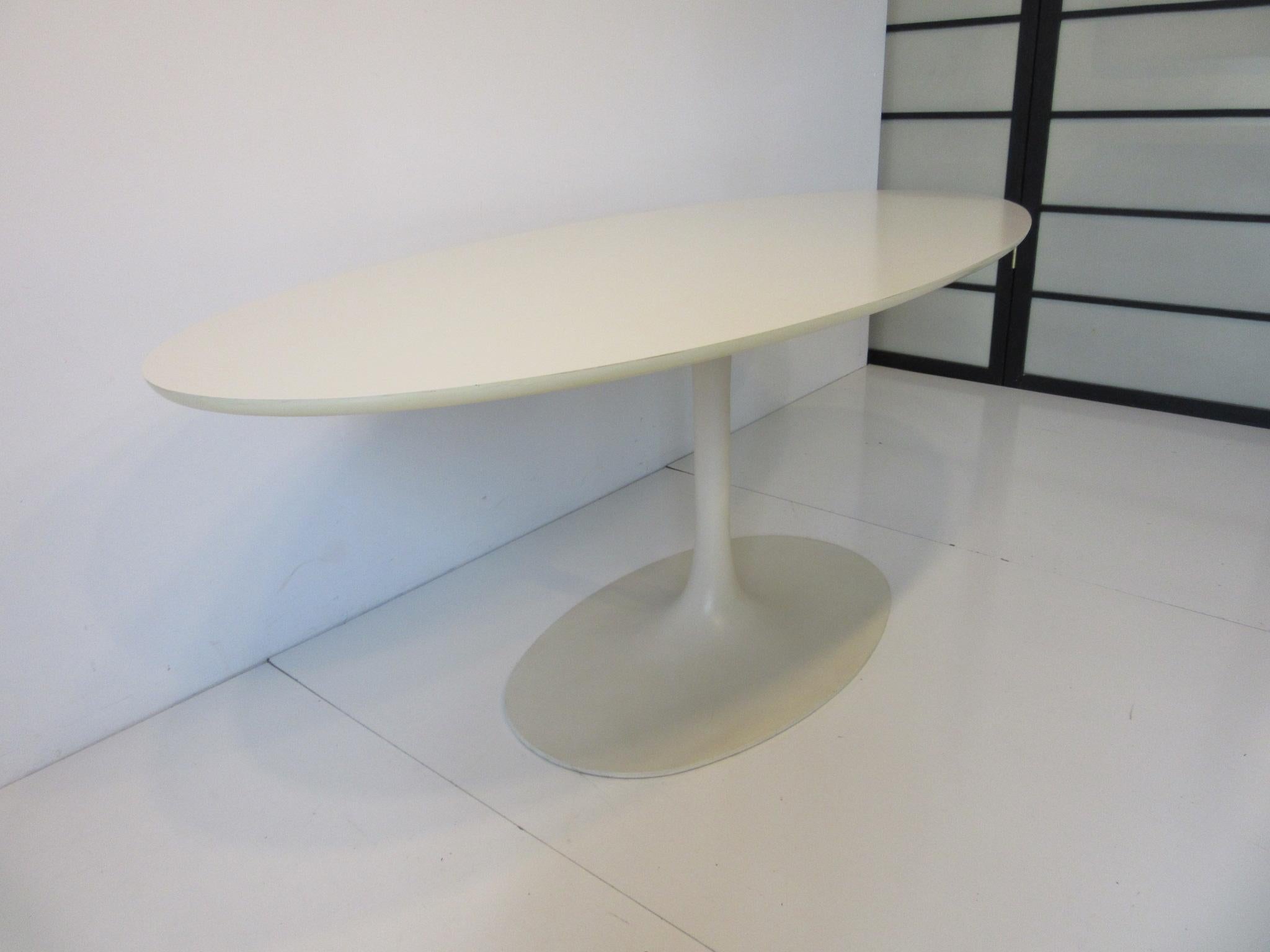 A hard to find narrow tulip writing table in the style of Eero Saarinen making this table desk perfect for that clean looking office or home office. Perfect for the lap top with an oval Formica topped surface, rolled edge and cast metal tulip base