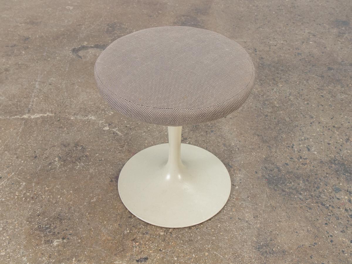 Vintage white tulip stool designed by Eero Saarinen for Knoll. This petite stool echoes the organic modern form of the designer's Pedestal Collection. Made of heavy cast aluminum, its substantial weight at the base ensures no loss of balance. Swivel