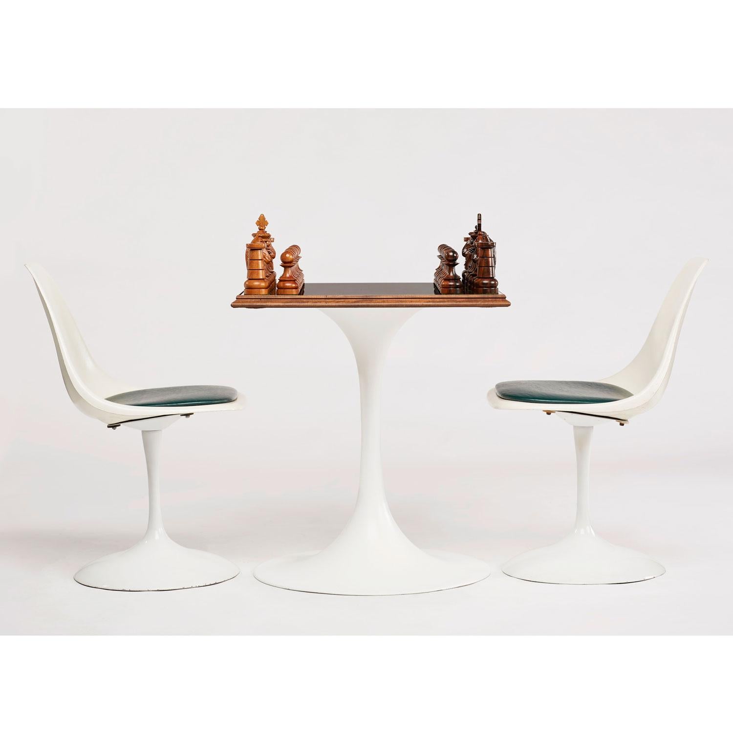 Truly one of a kind ebony wood chess set gaming table. The large chess board is mounted to a vintage, Mid-Century Modern tulip table and paired with two Saarinen style green padded chairs. Chess board has a custom cut-glass top which allows the