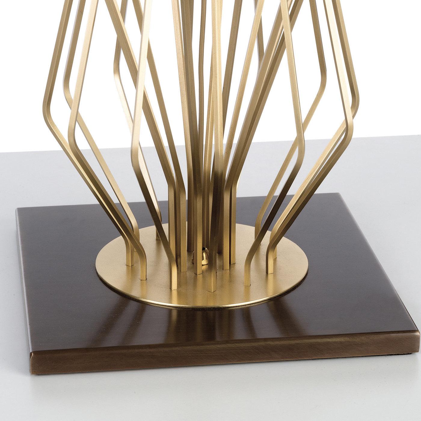 Part of the Saba collection, this table lamp features a contemporary design that is striking to behold and will make a statement in a modern decor. Its standout piece is the body, resting on a bronzed brass square base and made up of a multitude of