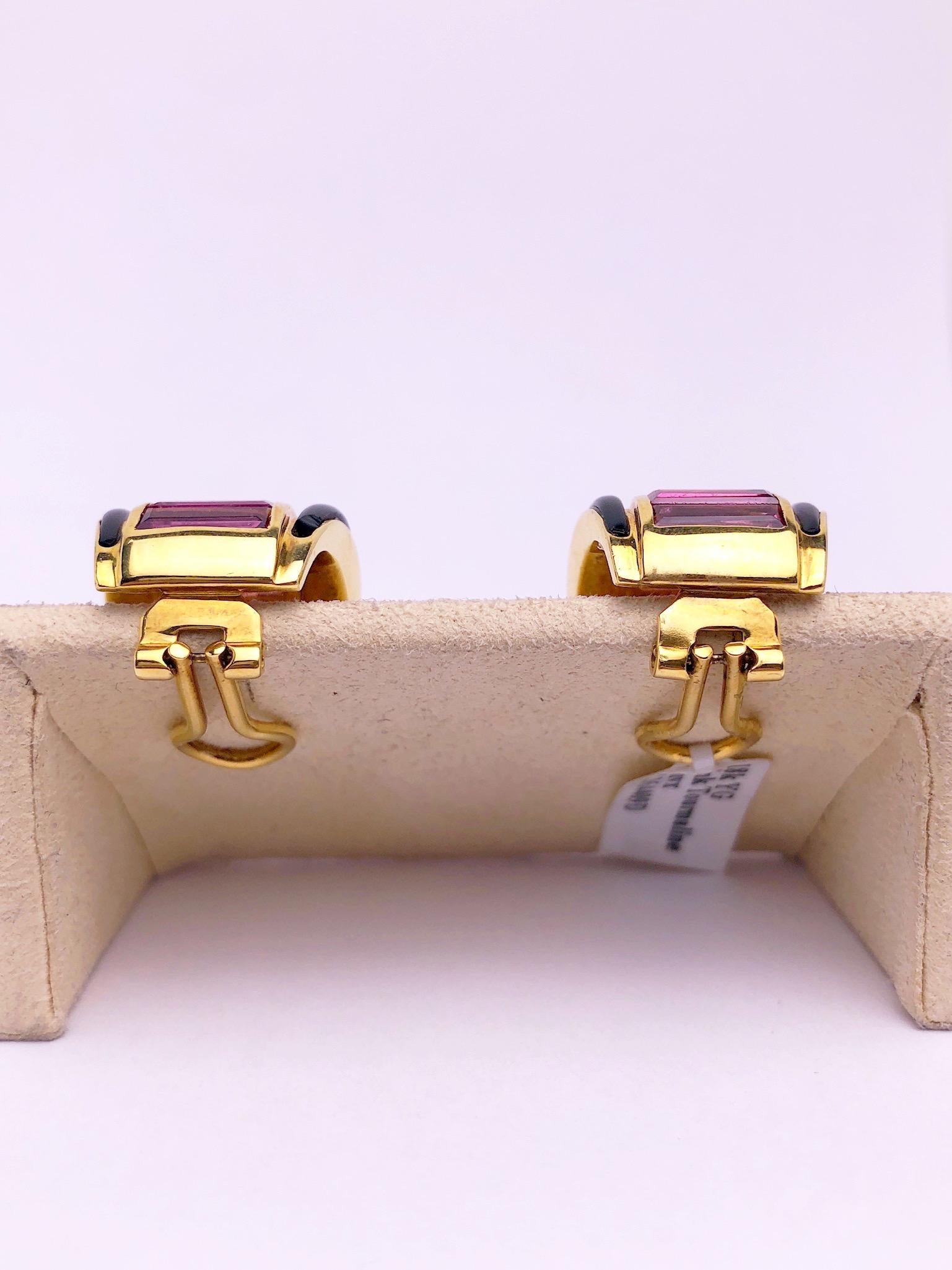 These 18 karat yellow gold earrings are designed with a row of Baguette Cut Pink Tourmaline stones set down the center with Black Onyx borders. The earrings measure approximately 3/4