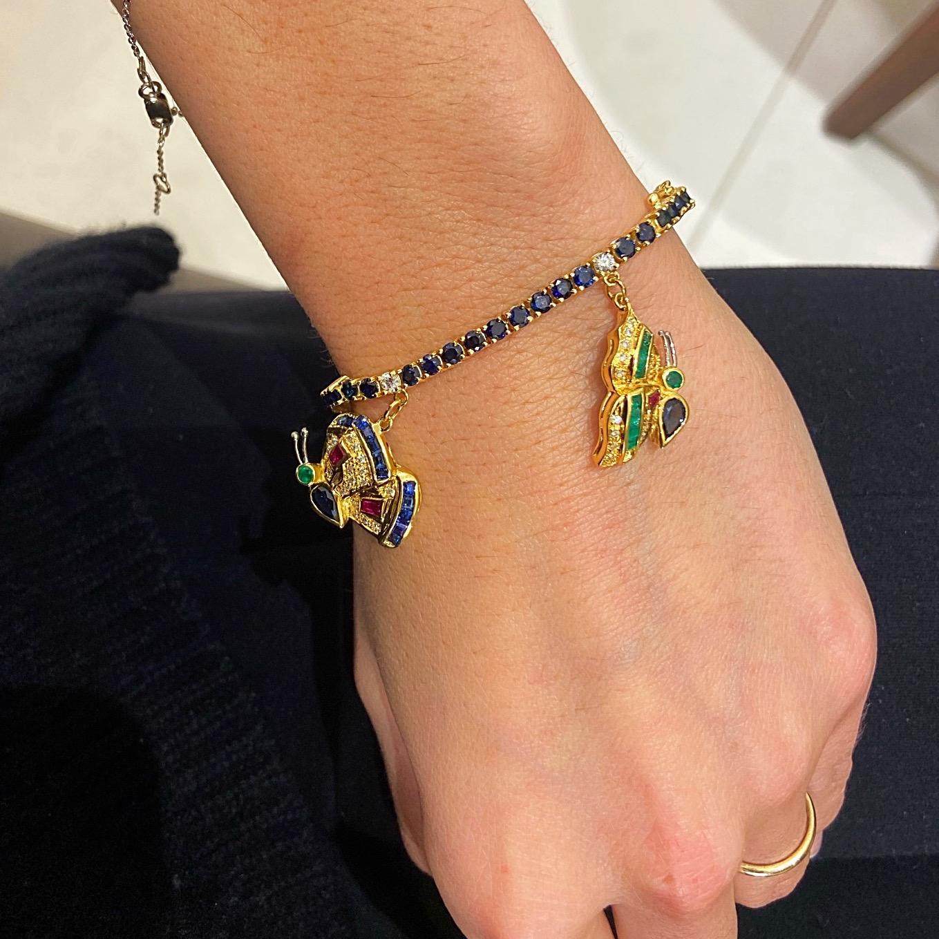 Created by the famed jewelers Sabbadini of Italy, this 18KT yellow gold charm bracelet is quite the unique piece.The blue sapphire bracelet is adorned with five butterfly charms, each detailed with diamonds, emeralds,rubies, blue and yellow