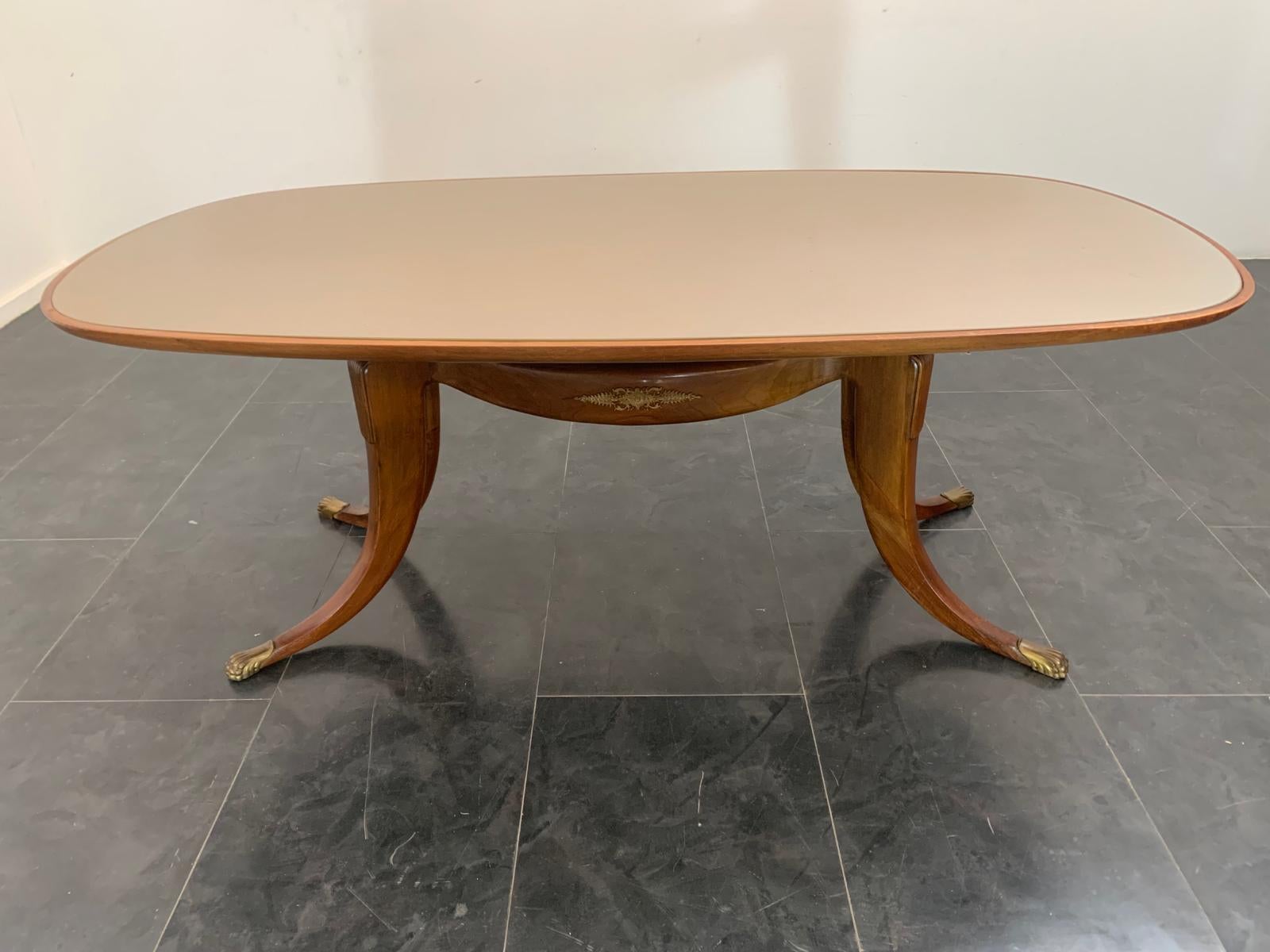 Excellent cabinet making for this table in solid rosewood. Four sabre legs with gilt bronze feline tips accommodate the gondola-shaped body in the centre, the whole supporting the oval top with back-treated glass. Gilded bronze details. The table