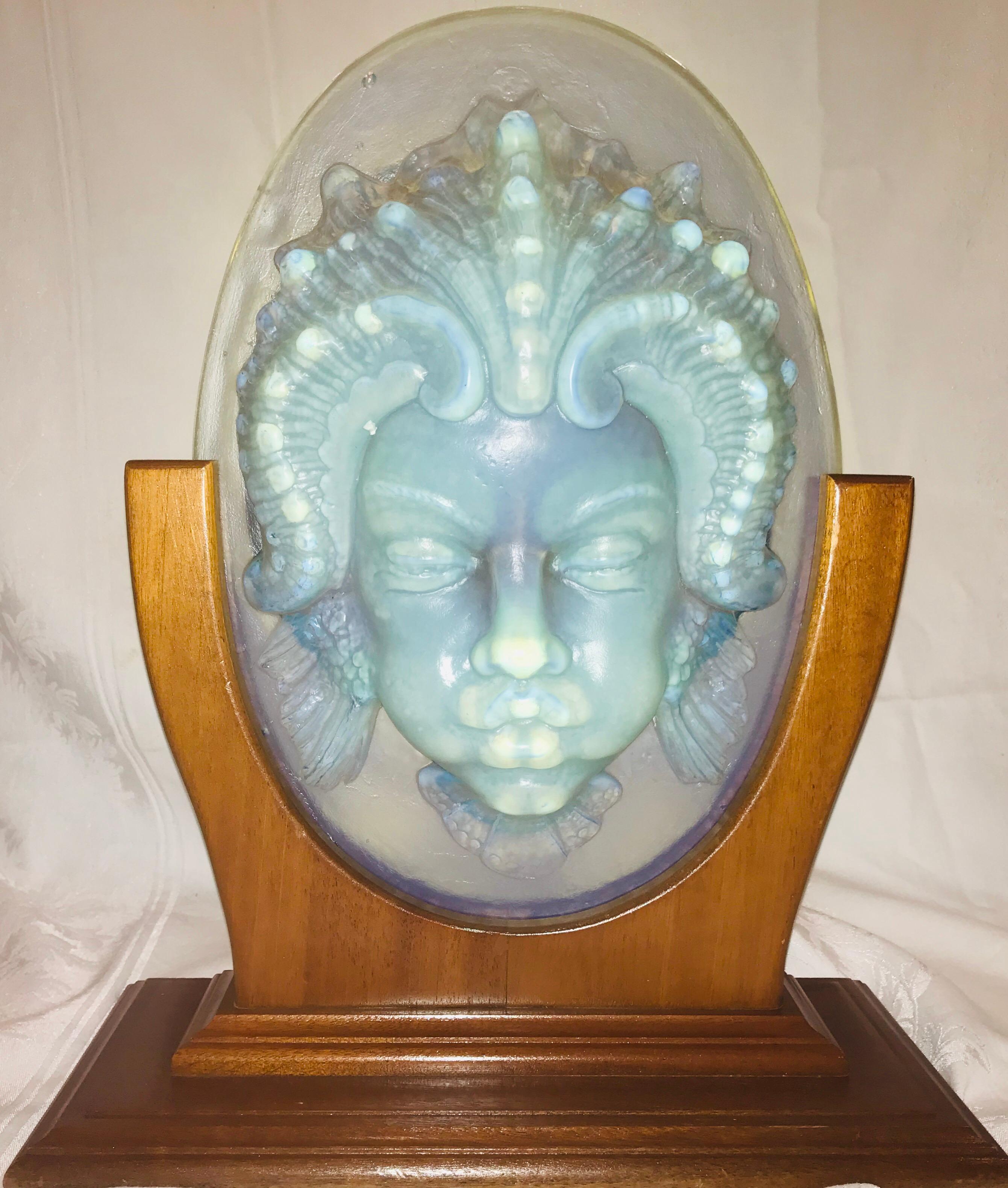 A Classic Sabino piece, this is a highly detailed opalescent glass mask of the face of Triton, son of Poseidon and Aphrodite. The hair and decorative motif are of a sea being with wavy hair, gills and mouth pursed as if to blow a gale. An amazing