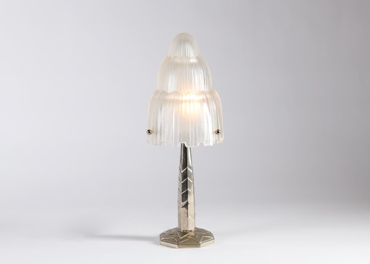 Cette lampe de table extraordinaire évoque le flux descendant de l'eau, à la fois dans son superbe abat-jour moulé et dans son imposant corps en bronze. 