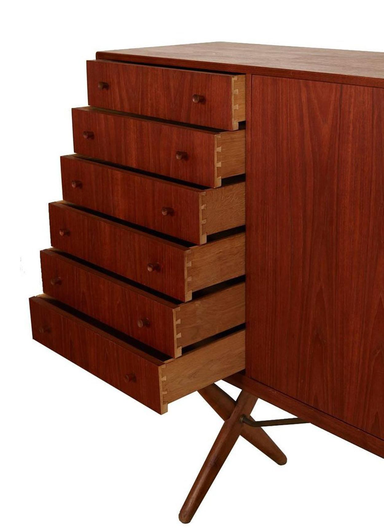 Danish modern teak credenza designed by Hans J. Wegner for Andreas Tuck. Features six dovetail drawers and two sliding doors concealing three adjustable shelves and shallow drawers or trays. This piece is in excellent vintage condition.

 