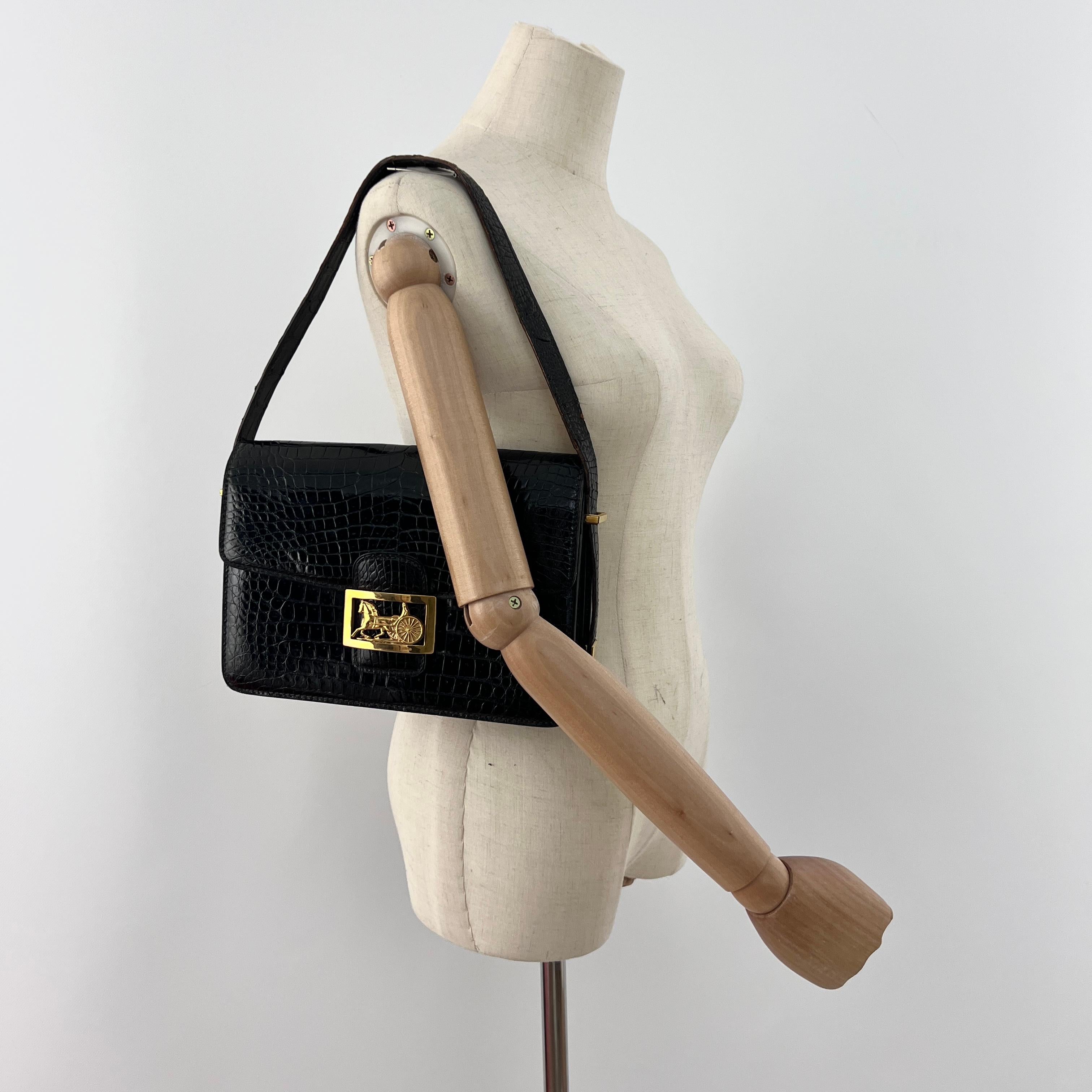 Magnifique sac à main CELINE modèle Triomphe  in coccodrillo di colore nero, caratterizzato da una decorazione dorata.
La borsa è dotata di un fermoir à rabat.
L'interno è composto da tre scompartimenti principali e da una poche plaquée zipée.
La