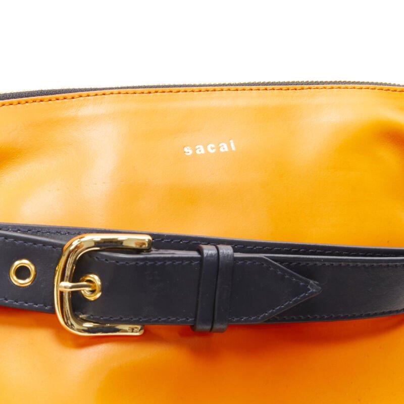 Bolso bandolera SACAI de piel naranja con cinturón azul marino y logotipo dorado en venta 2