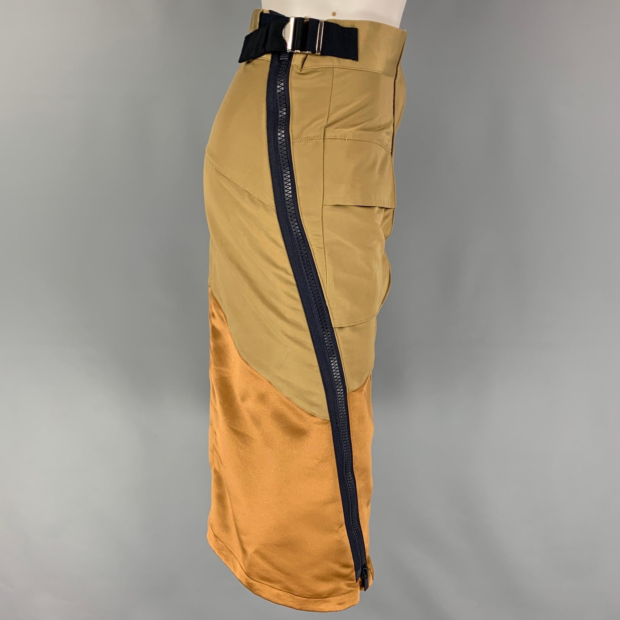 SACAI skirt comes in a khaki & gold color block cotton blend featuring a pencil style, patch pockets, exposed zipper details, adjustable side tabs, and a hidden zip & snap button closure. Made in Japan. 

Very Good Pre-Owned Condition.
Marked: