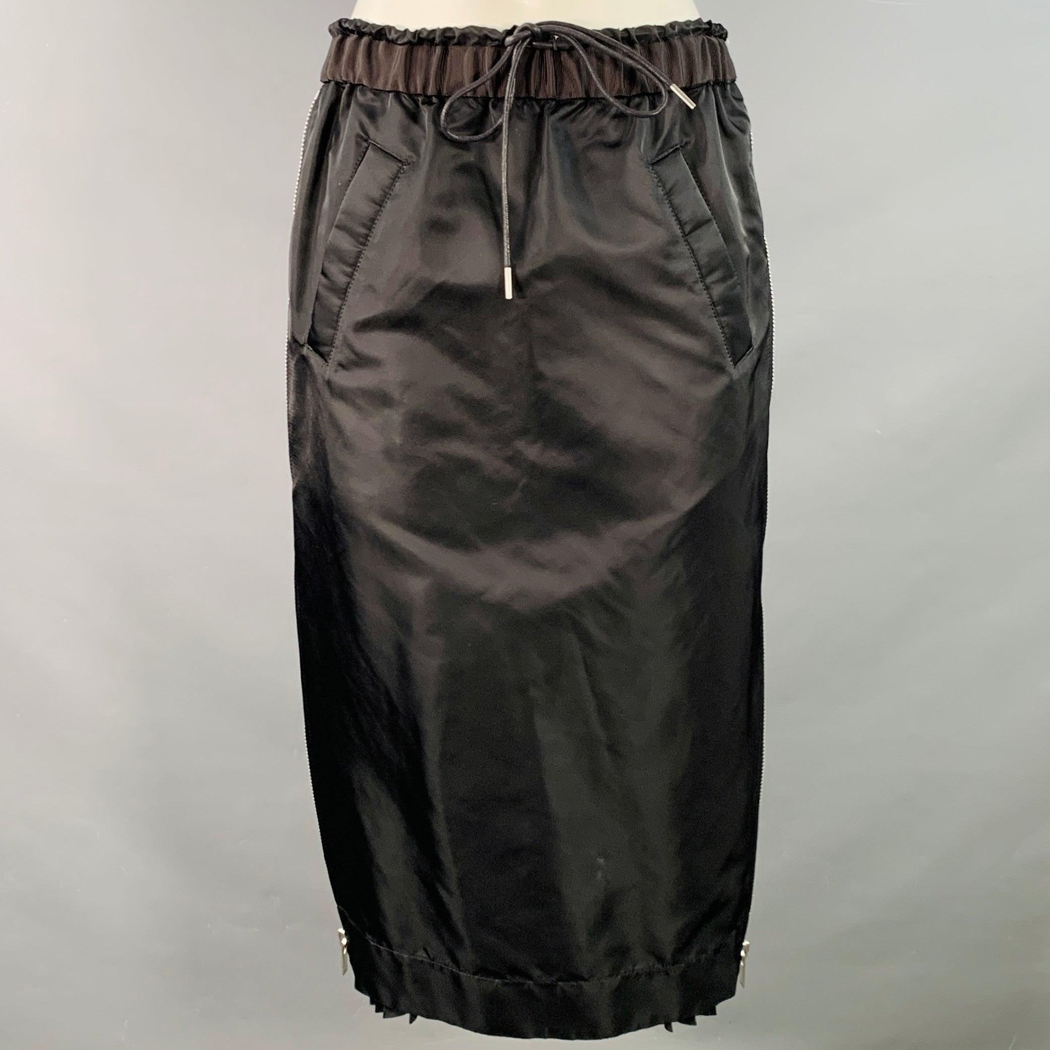 SACAI skirt
in a black nylon blend fabric featuring a pencil style with silver tone metal side zippers, pleated panels which are revealed when unzipped, and drawstring waistband closure. Made in Japan.Excellent Pre-Owned Condition. 

Marked:   JP 2