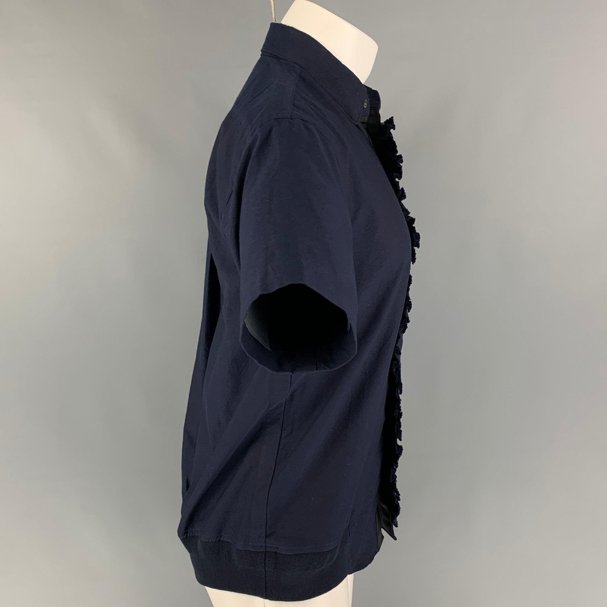 SACAI short sleeve shirt comes in a navy cotton featuring a ruffled trim, elastic hem, patch pocket, spread collar, and a button up closure.
Very Good
Pre-Owned Condition. 

Marked:   1 

Measurements: 
 
Shoulder: 17 inches  Chest: 38 inches 