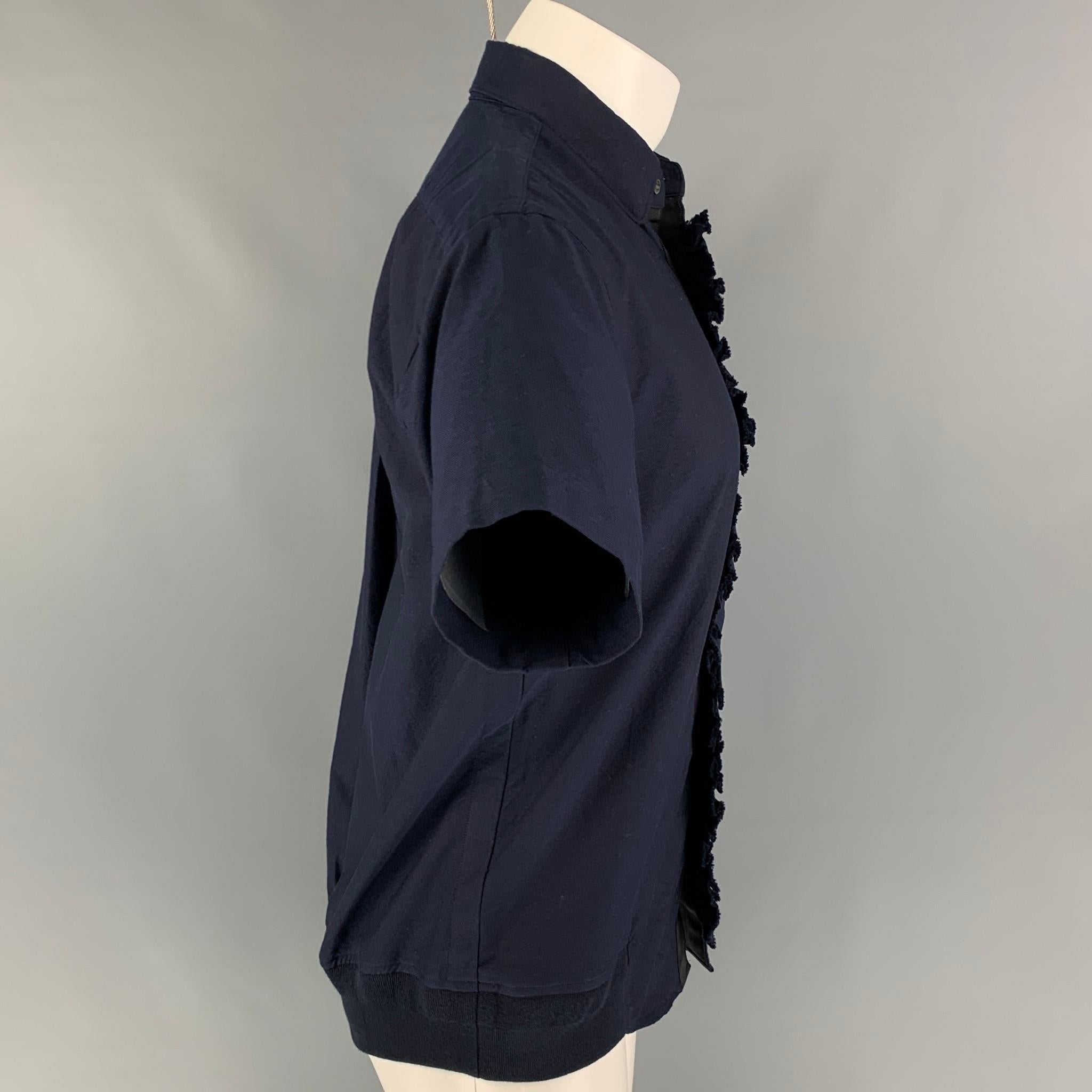 SACAI short sleeve shirt comes in a navy cotton featuring a ruffled trim, elastic hem, patch pocket, spread collar, and a button up closure. 

Very Good Pre-Owned Condition.
Marked: 1

Measurements:

Shoulder: 17 in.
Chest: 38 in.
Sleeve: 9