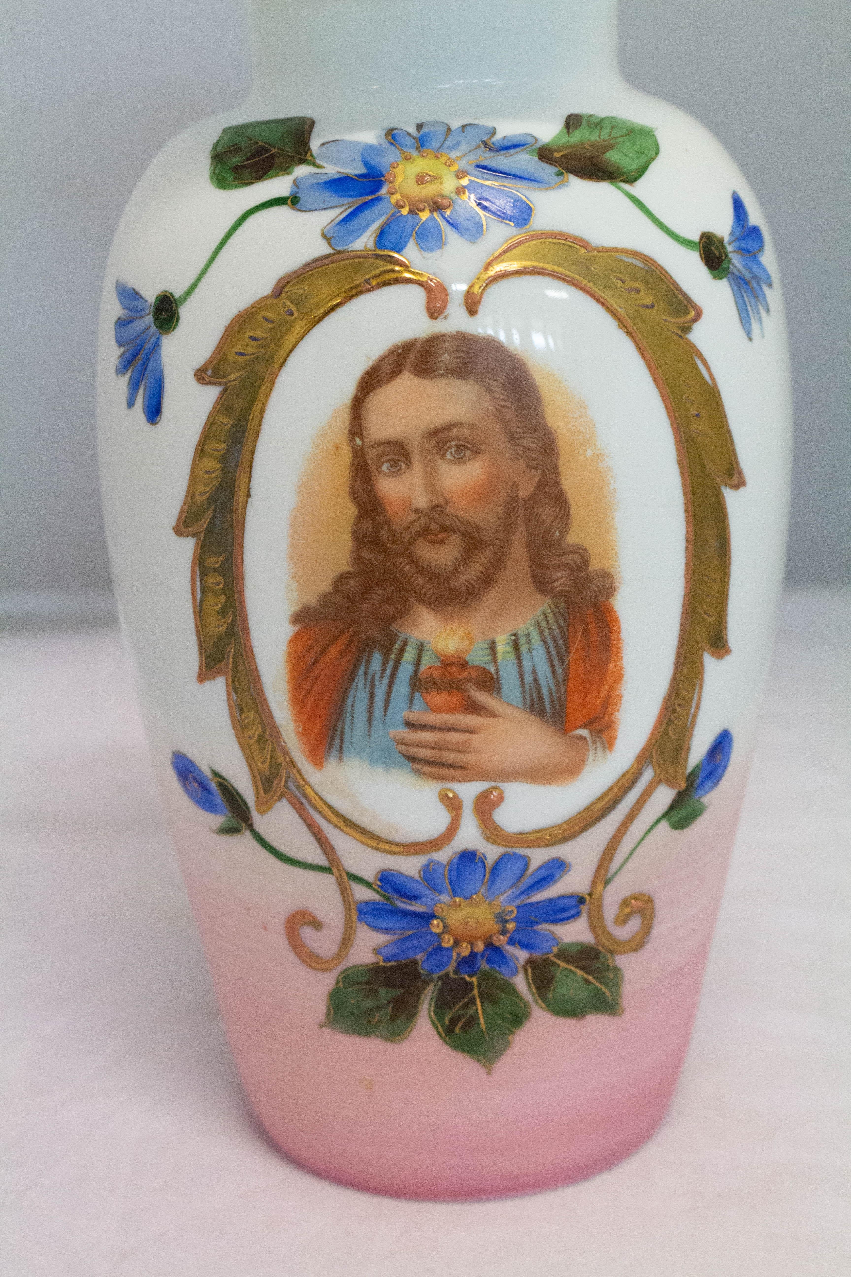 Opaline vase representing Sacred Heart of Christ
The Christ is surrounded by a golden painting frame and floral decoration.
The border of the mouth is also painted with gold.
Good antique condition.
 
For shipping:
Measures: 16 x 16 x 29cm.