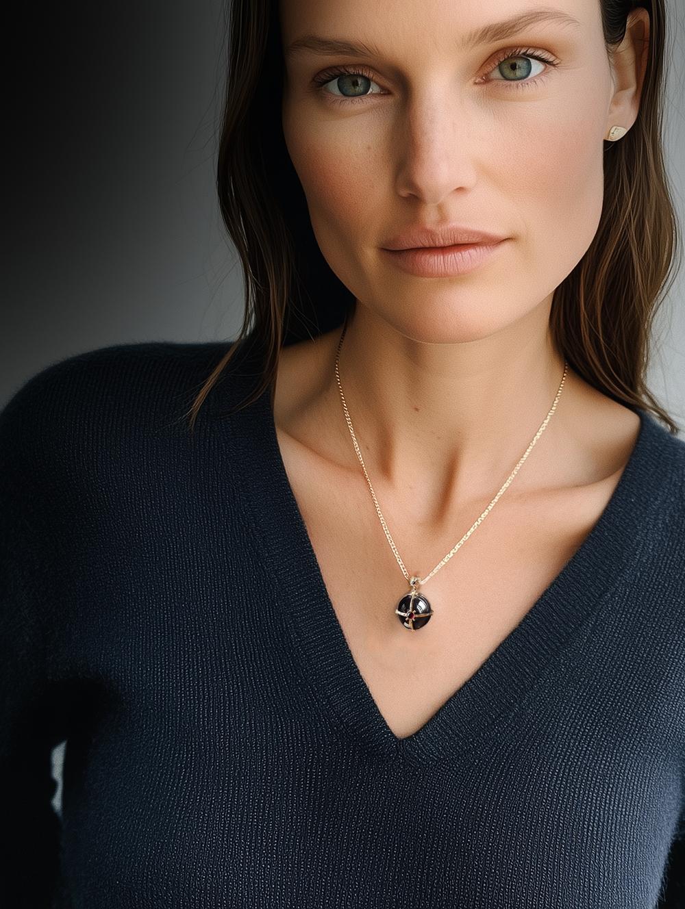 Este collar colgante de oro amarillo de 18 quilates con motivo religioso presenta una piedra de ónice abovedada (radio: 1 cm) encerrada en una escultural estructura de oro. 

Es una pieza hecha a medida que se puede fabricar en Alemania con rubíes,