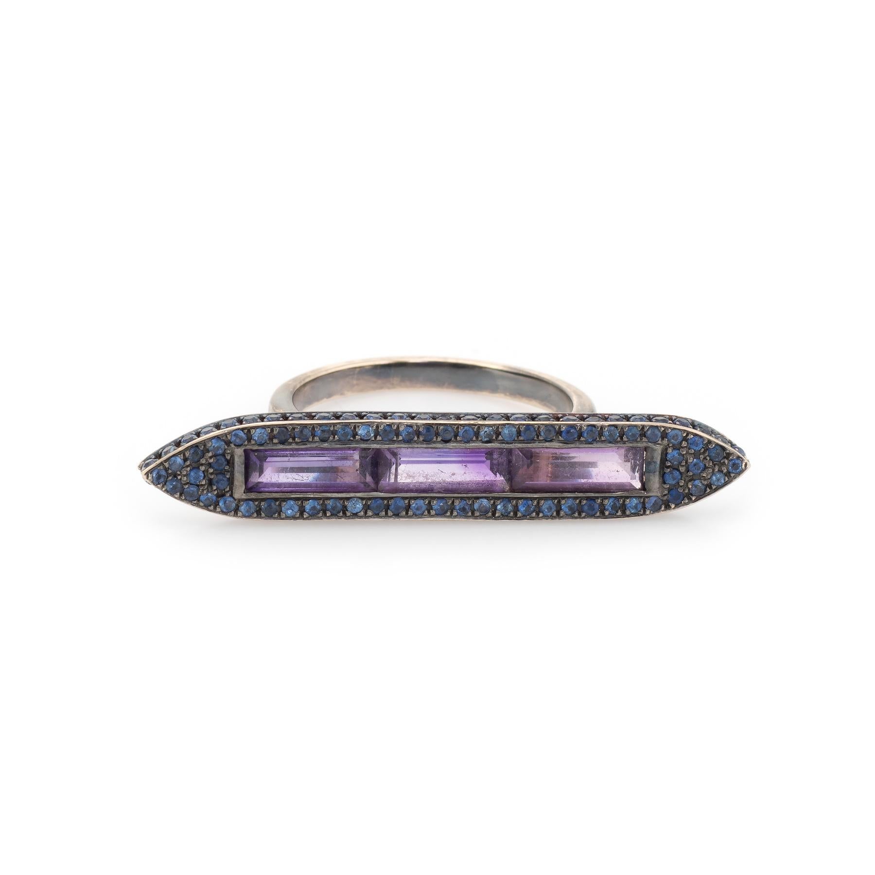 Finely detailed Ralph Masri Sacred Windows ring, crafted in 18 karat blackened white gold. 

Straight baguette cut amethysts measures 8mm x 2.5mm (each) and total an estimated 0.75 carats. Blue sapphires are pave set into the mount and total an