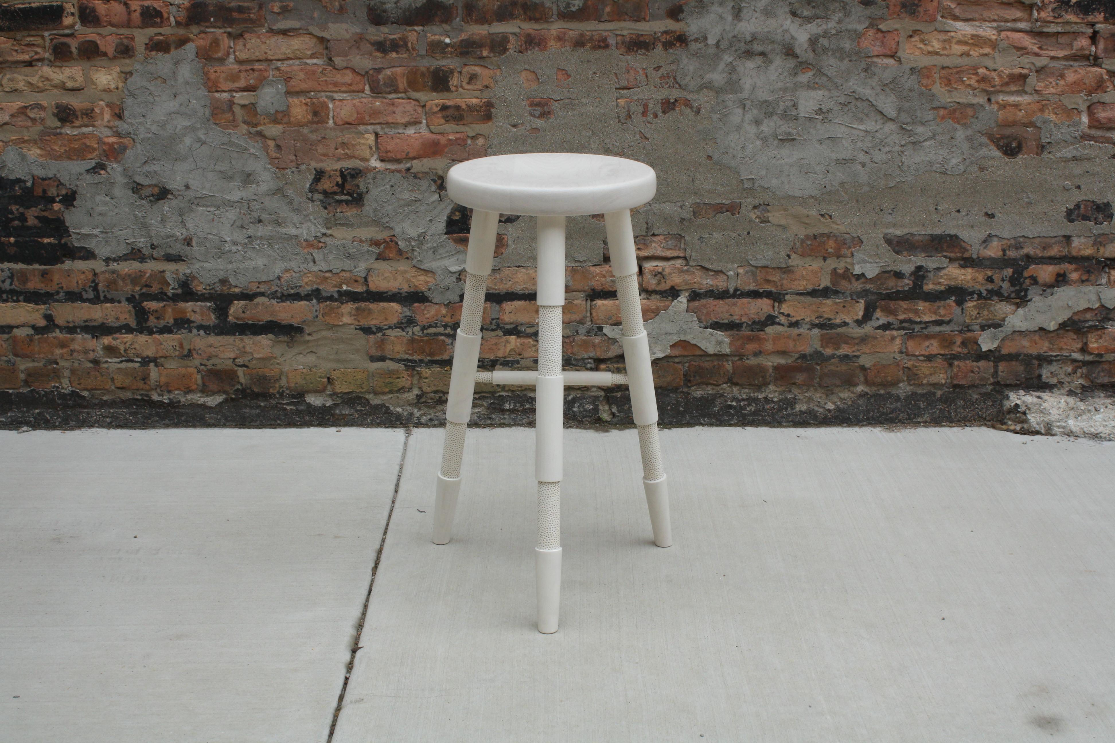 Handmade in Chicago by Laylo Studio, this solid wood stool features lathe-turned and textured legs that are joined to the hand-carved seat using through wedged, tapered tenons - a tried and true method of joinery found in Windsor chairs - which are
