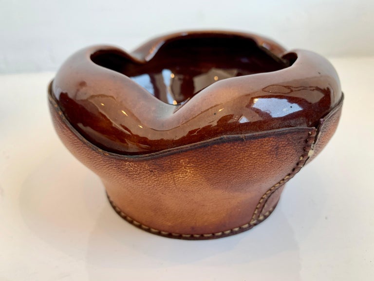 Handsome leather and ceramic ashtray/catchall by Longchamps. Stamped with Lonchamp - France and logo. Saddle leather base with contrast stitching. Deep brown ceramic dish sewn into leather. Great sculptural piece. Perfect ashtray or bowl for keys by