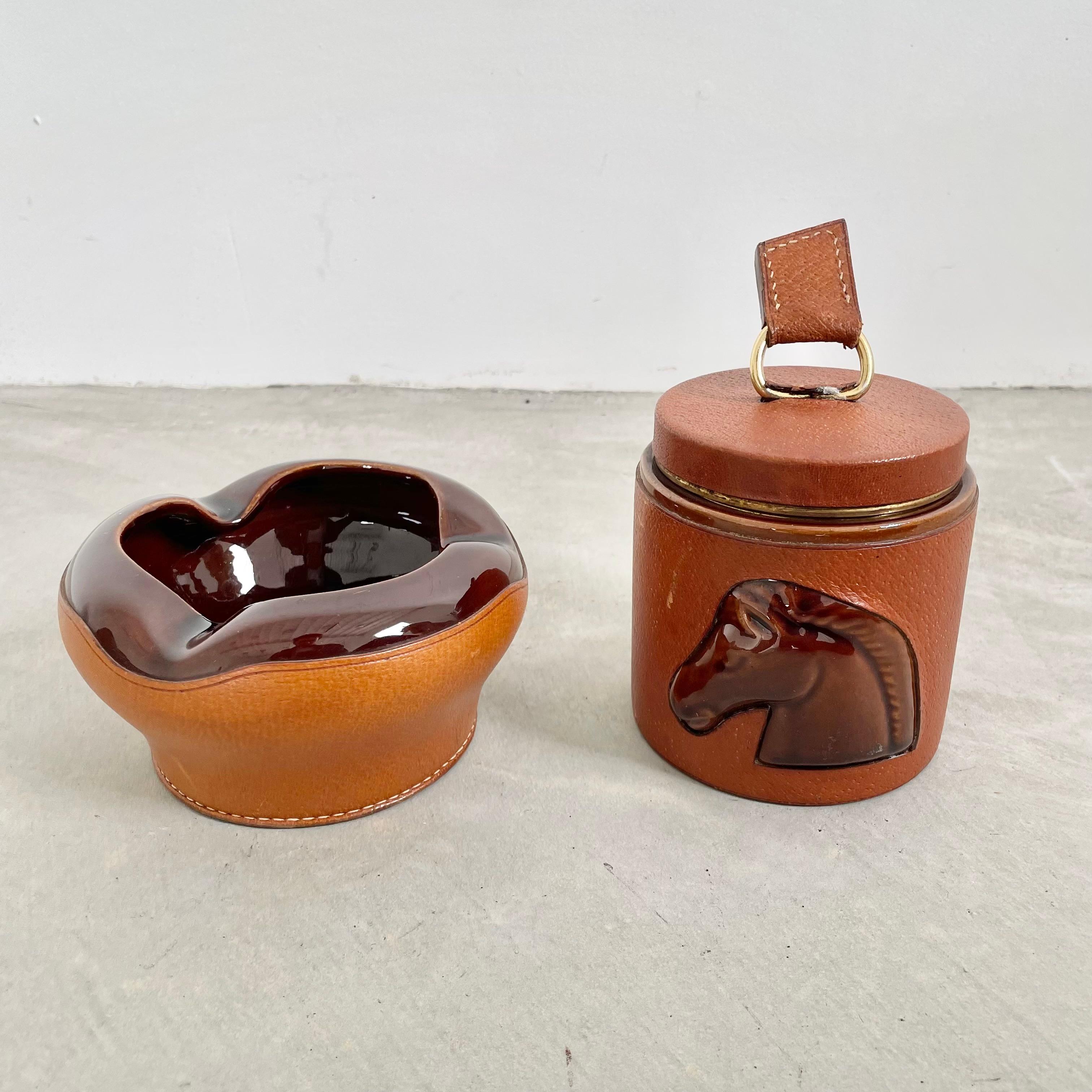 Handsome leather and ceramic smoking set by Longchamp. Cigarette holder opens up to reveal a cigarette dispenser which fans out and compacts back down when pushing back into the jar. Stamped with Lonchamp - France and logo on the base of the