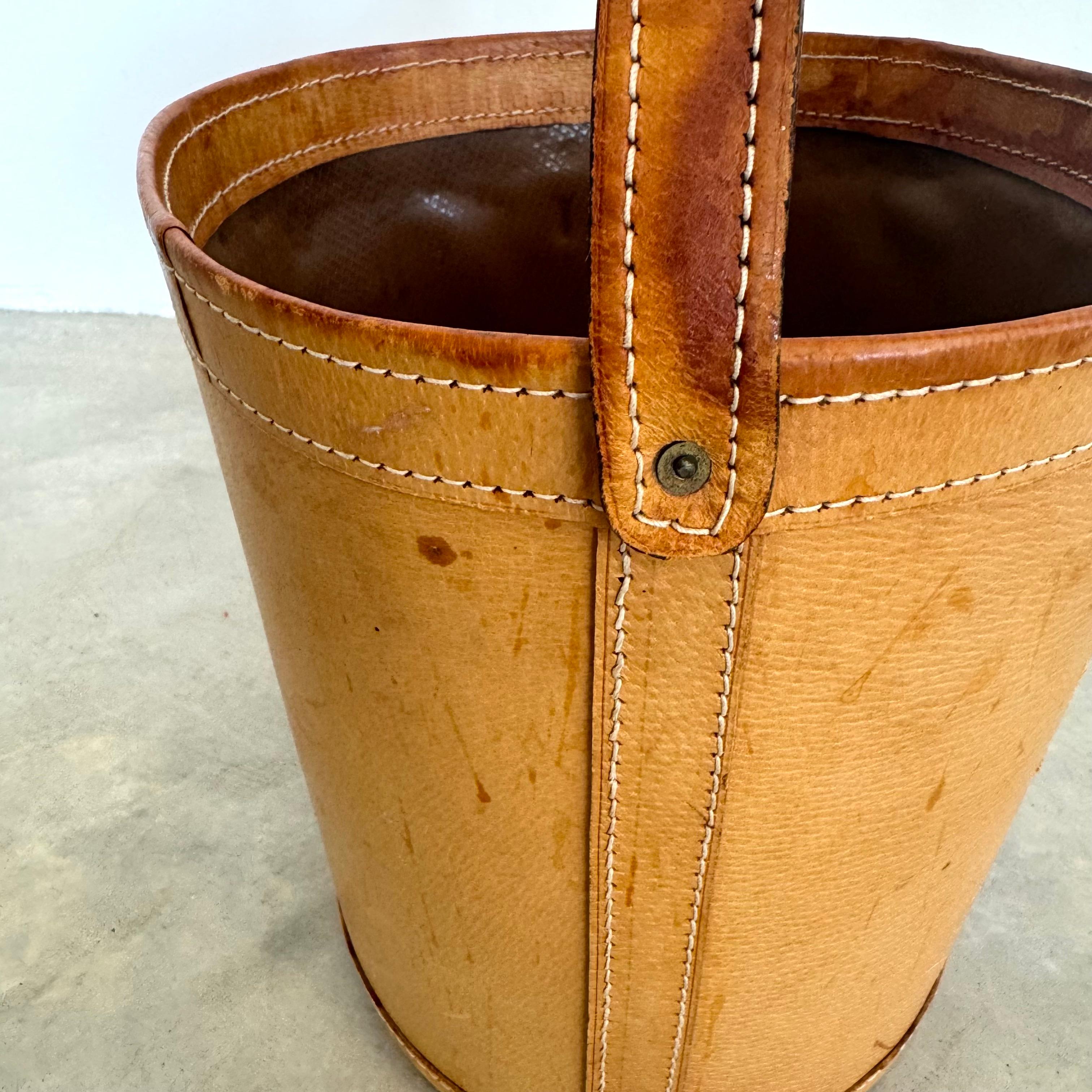 French saddle leather waste bin in the style of Jacques Adnet, with a substantial leather strap handle. Great coloring to saddle leather. Contrast stitch throughout. Plastic lining inside the bin to protect the leather against soiling or staining.