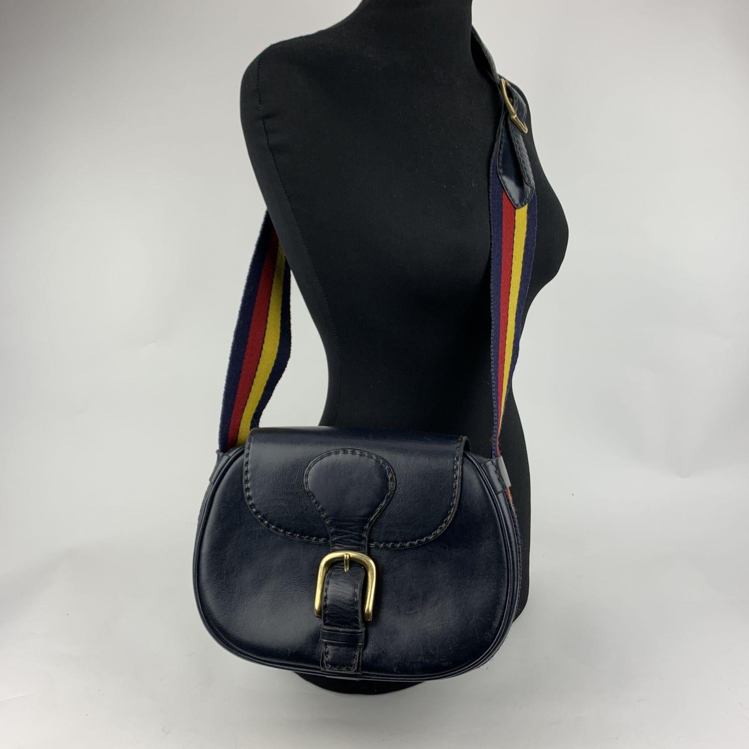 Beautiful shoulder bag crafted in navy blue leather by Saddlers Union. The model is inspired by the 'Hunting bags' worn during outdoor hunting trips. The bag features a flap with front buckle closure and an adjustable striped canvas shoulder strap.