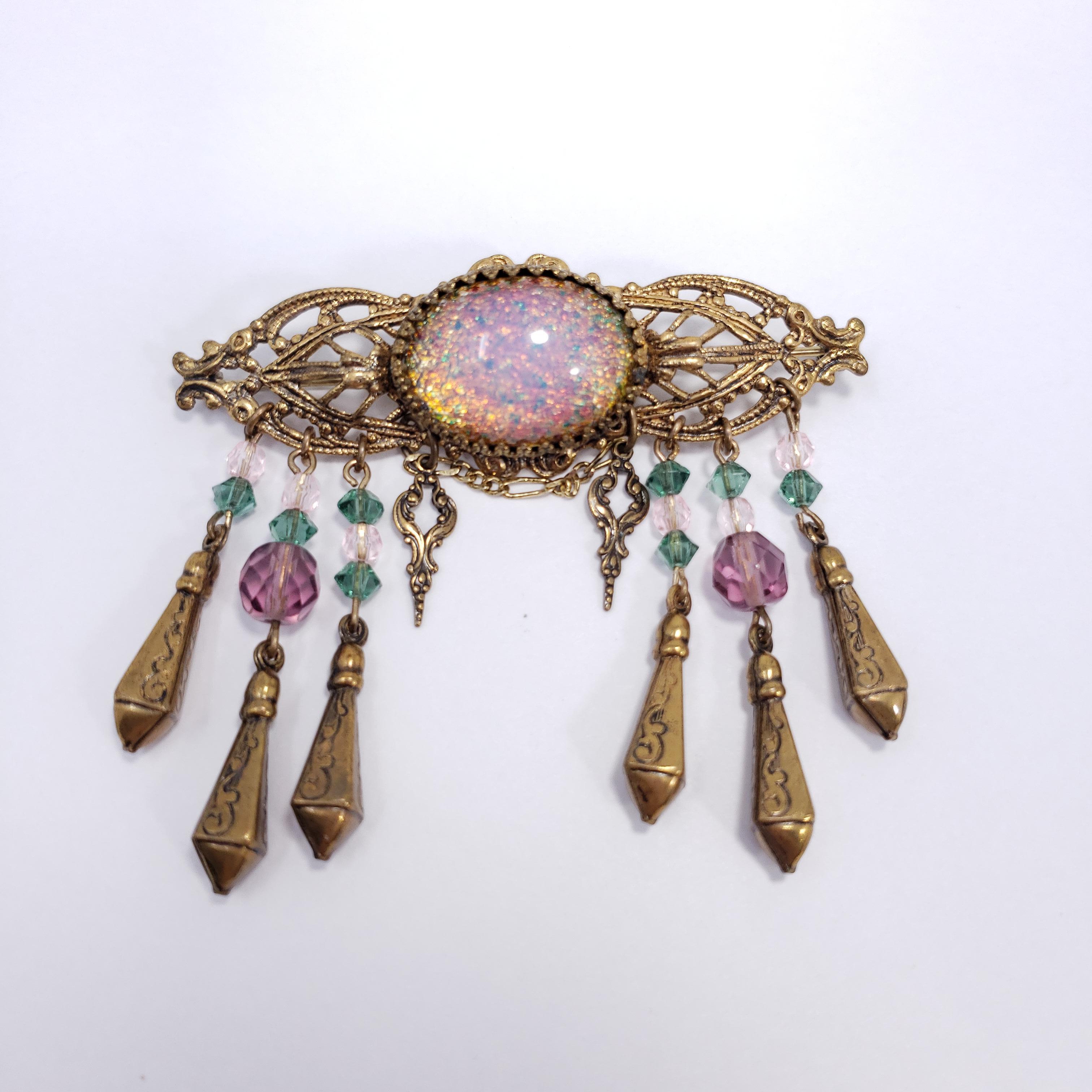 Gorgeous pin brooch by Sadie Green. Features a centerpiece cosmic faux opal cabochon in a Victorian-style setting, accented with faceted crystals and dangling accents.

Marks / hallmarks / etc: Sadie Green