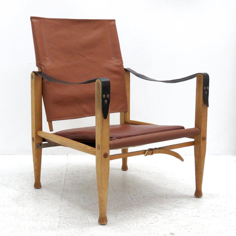 Stunning safari chair designed by Kaare Klint for Rud. Rasmussen’s Snedkerier, with patinated ash frame, seat, back, straps and loose cushion in leather, designed in 1933, produced 1969, reupholstered in slightly varying shades of cognac to burgundy