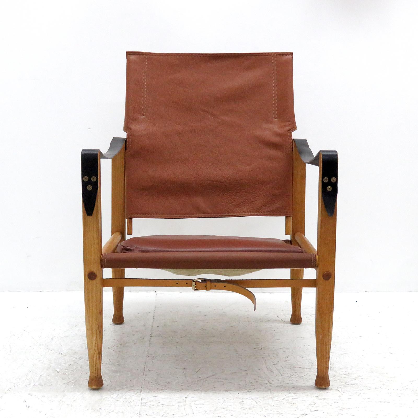 Stunning safari chair designed by Kaare Klint for Rud. Rasmussen’s Snedkerier, with patinated ash frame, seat, back, straps and loose cushion in leather, designed in 1933, produced 1969, reupholstered in slightly varying shades of cognac to burgundy