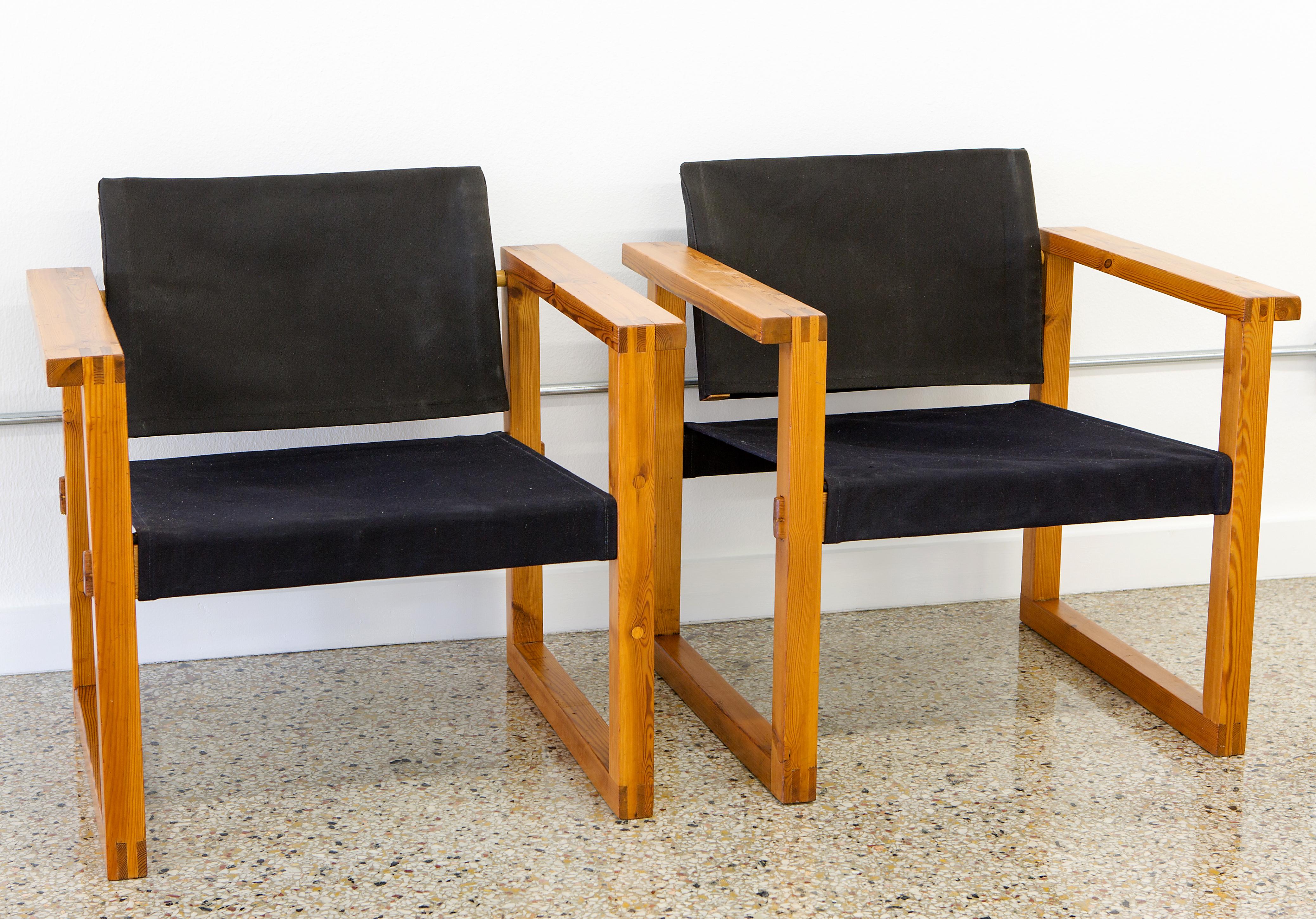 Pair of Finn Farmer safari / director's chairs. Reupholstered in slingback black canvas, circa 1960s. Richly grained pine frame dovetailed for support, sturdiness and as a design element. Back rest pivots on its steel frame to adjust for maximum