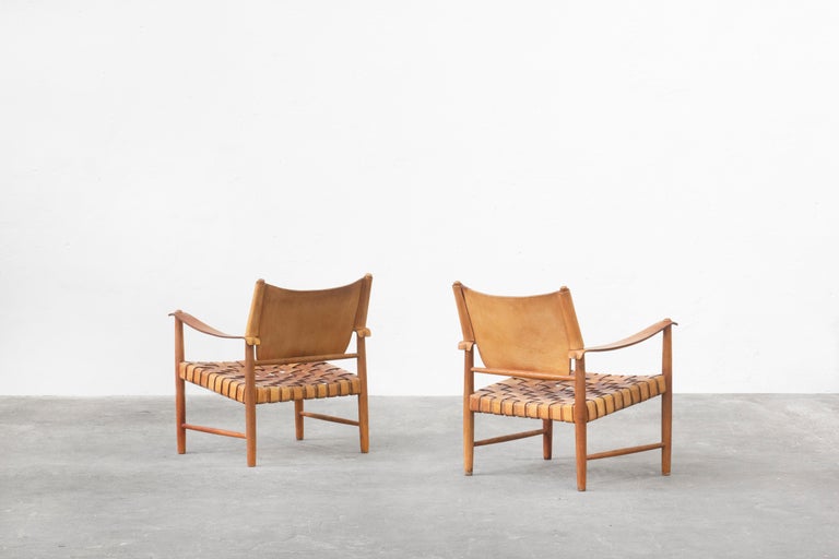 Very beautiful lounge chairs made out of oak and brown-cognac leather, made in Germany in the 1950s. 
Both chairs are in very good vintage condition with signs of use and beautifully patinated leather and oak frame. 

Absolutely rare and unique
