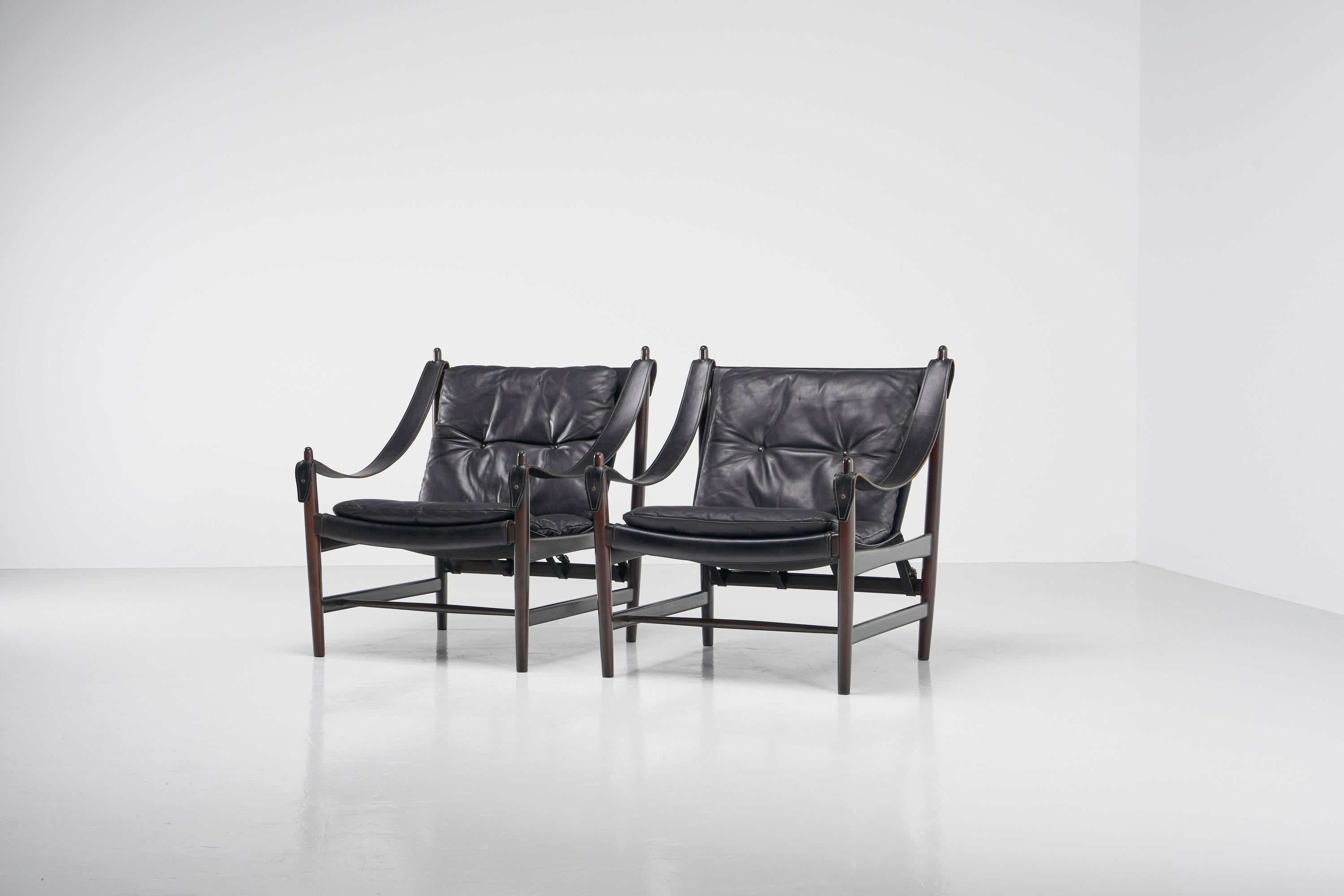 Stunning Nordic pair of safari lounge chairs in original condition, made in Norway 1965. These fantastic chairs are made of solid mahogany frames and thick black saddle leather seats, and are in a very good and original condition. The chairs are
