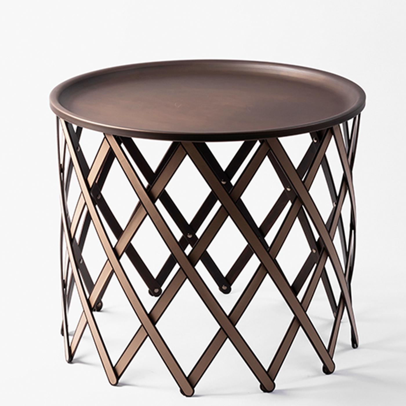 Suitable for both indoor and outdoor use, this foldable table features a round burnished brass tray-top on a crisscrossed base of flat wooden sticks covered with brown leather. It is available in other colors and large and medium size.