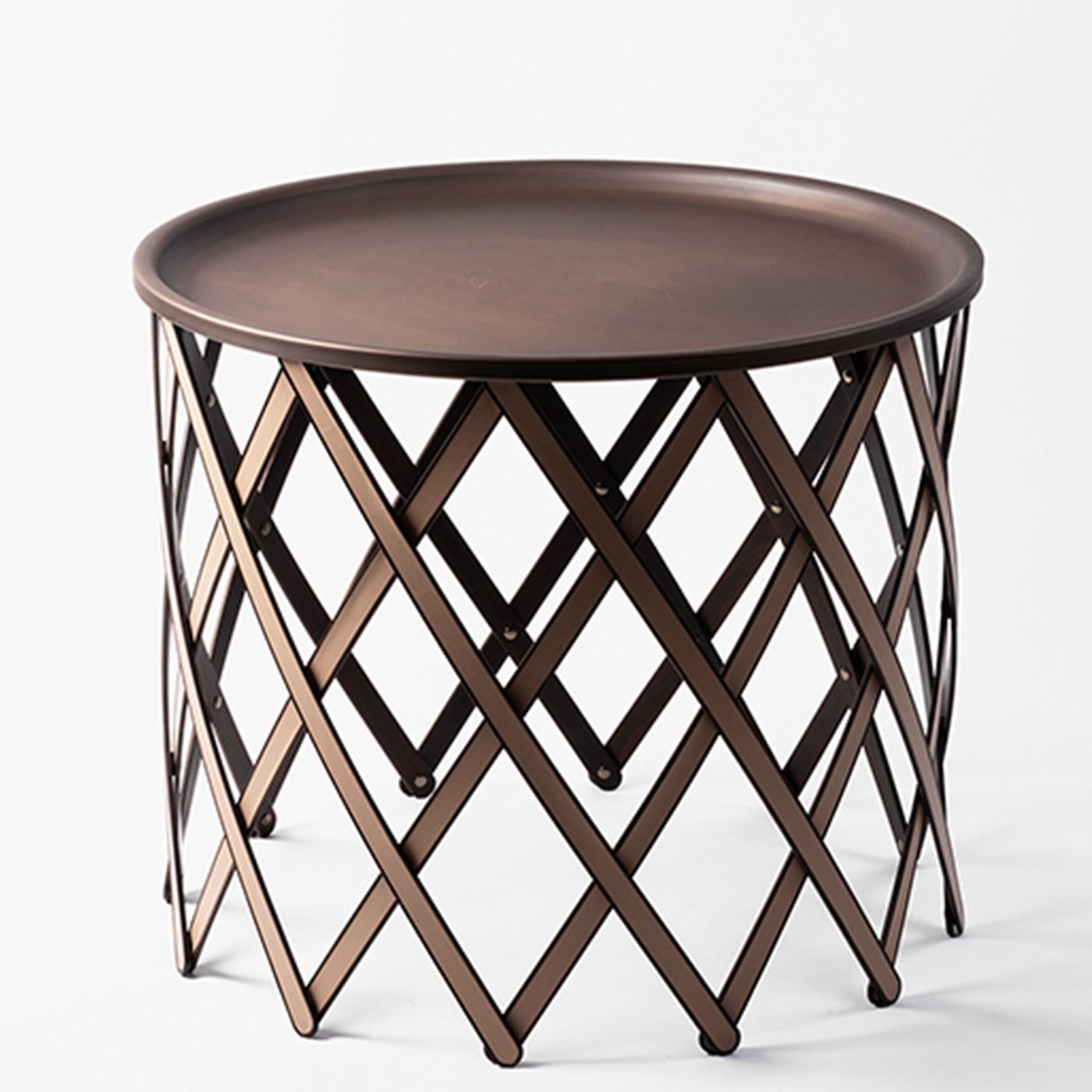 Suitable for both indoor and outdoor use, this foldable table features a round burnished brass tray-top on a crisscrossed base of flat wooden sticks covered with brown leather. It is available in other colors and large and medium size.