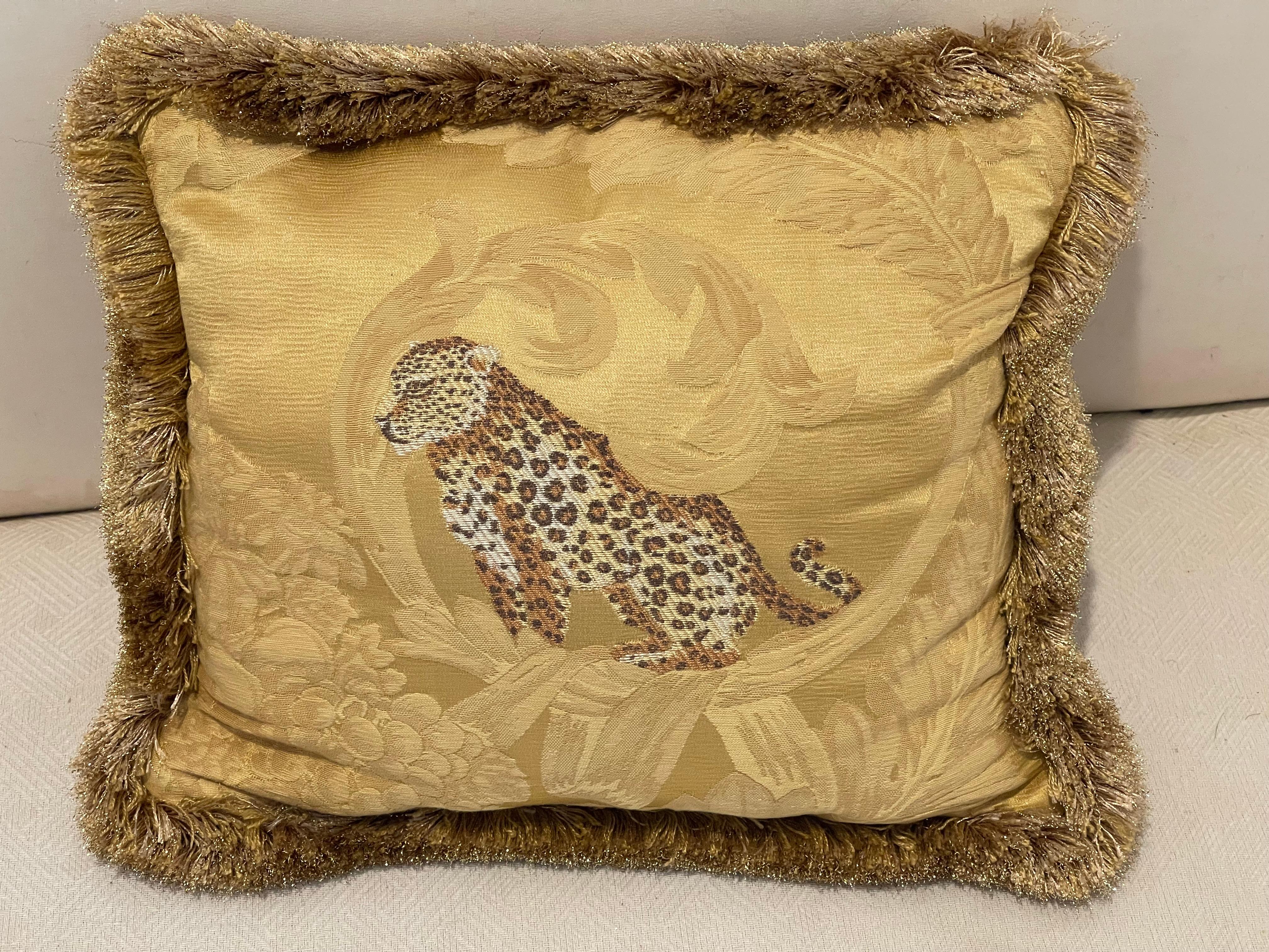 Small cute lumbar pillow in yellow gold brocade with tiger tapestry and fringes .