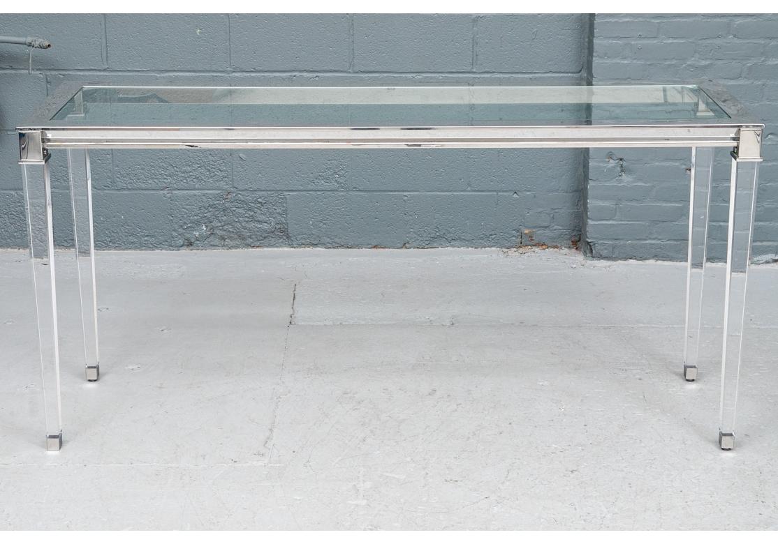 Fine table console contemporaine avec structure en inox et plateau en verre avec une frise angulaire encastrée en miroir en dessous. Monté sur des pieds acryliques de forme carrée et effilée, avec des plateaux et des pieds en acier inoxydable.