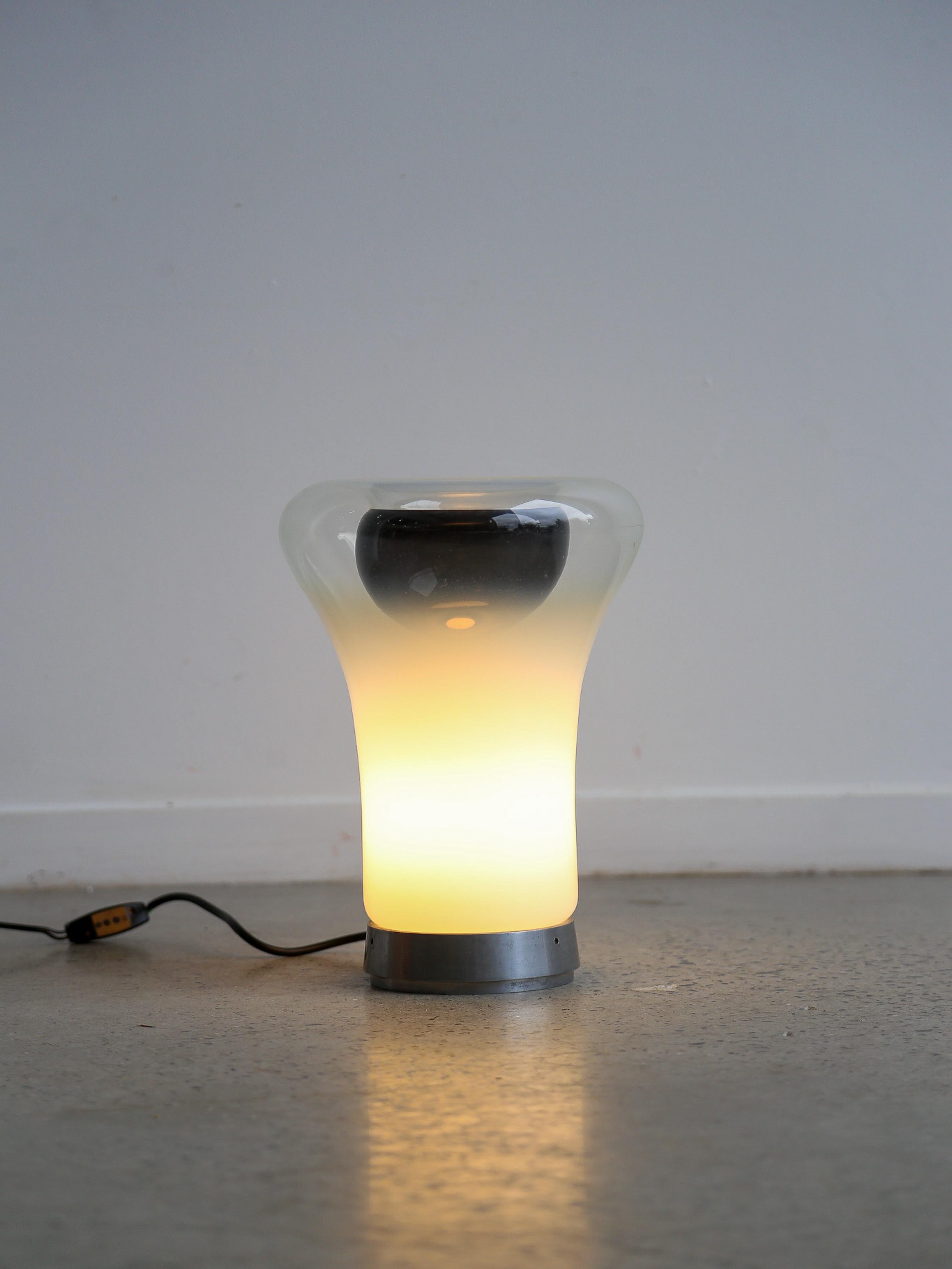 Designed by Angelo Mangiarotti and produced by Artemide in 1967, the lamp is made with a metal ring that supports a blown glass diffuser. Thanks to it's shaded surface it can dim the light of the light source. 

Italian architect, designer, teacher