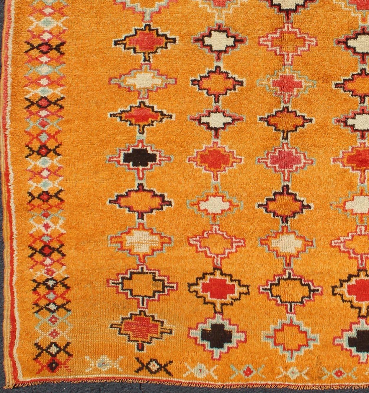 Saffron color antique Moroccan carpet with geometric patterns with orange, red, black, charcoal, white, light blue and ivory, rug H8-0802, country of origin / type: Morocco / Tribal, circa 1920.

Crafted in the early 20th century, this gorgeous