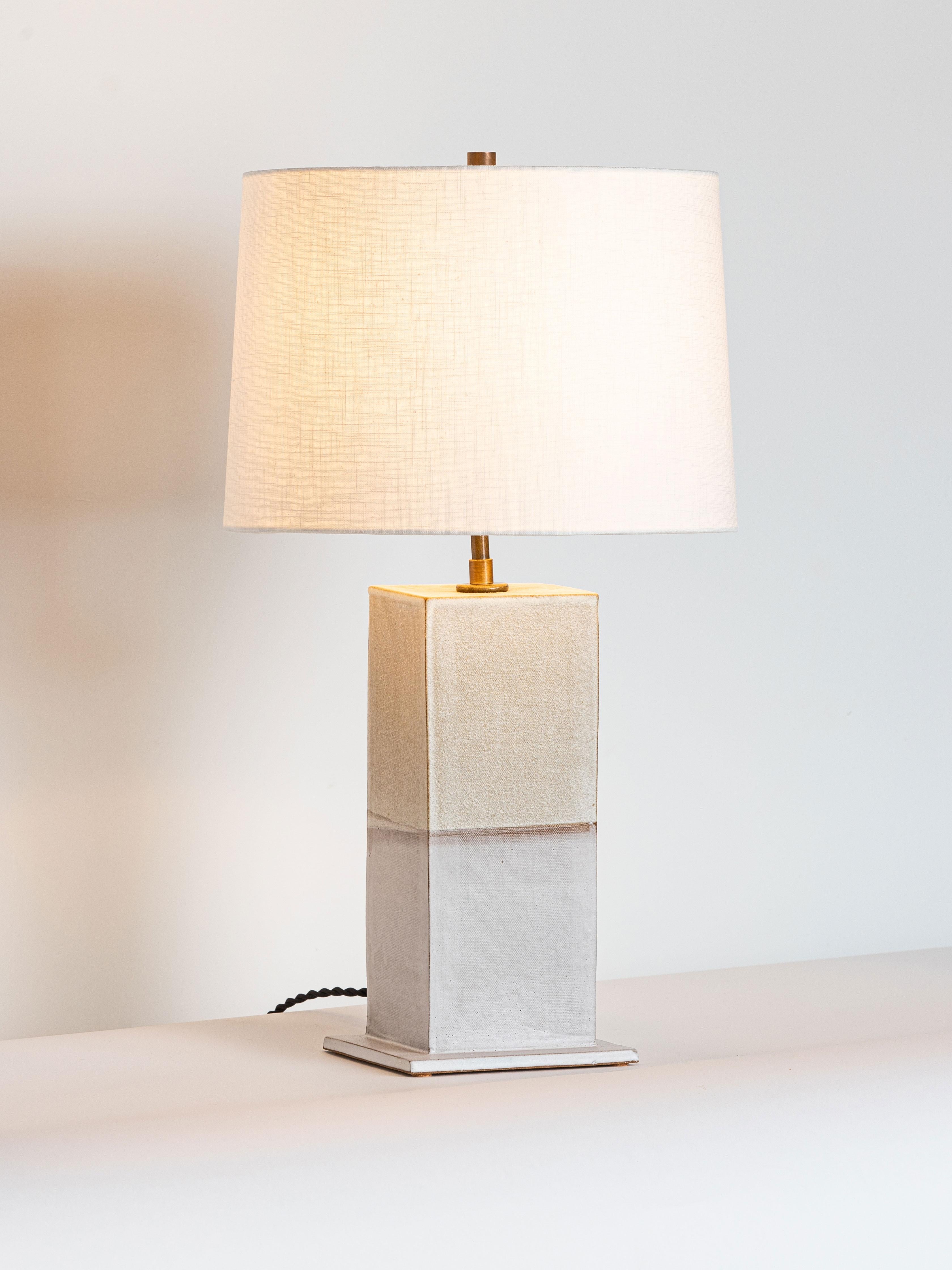 Our stoneware Sag Harbor lamp is handcrafted using slab-construction techniques.

Finish

- Dipped glaze, two colors, pictured in parchment & chalk 
- Antique brass fittings
- Twisted black-cloth cord
- Full-range dimmer socket
-