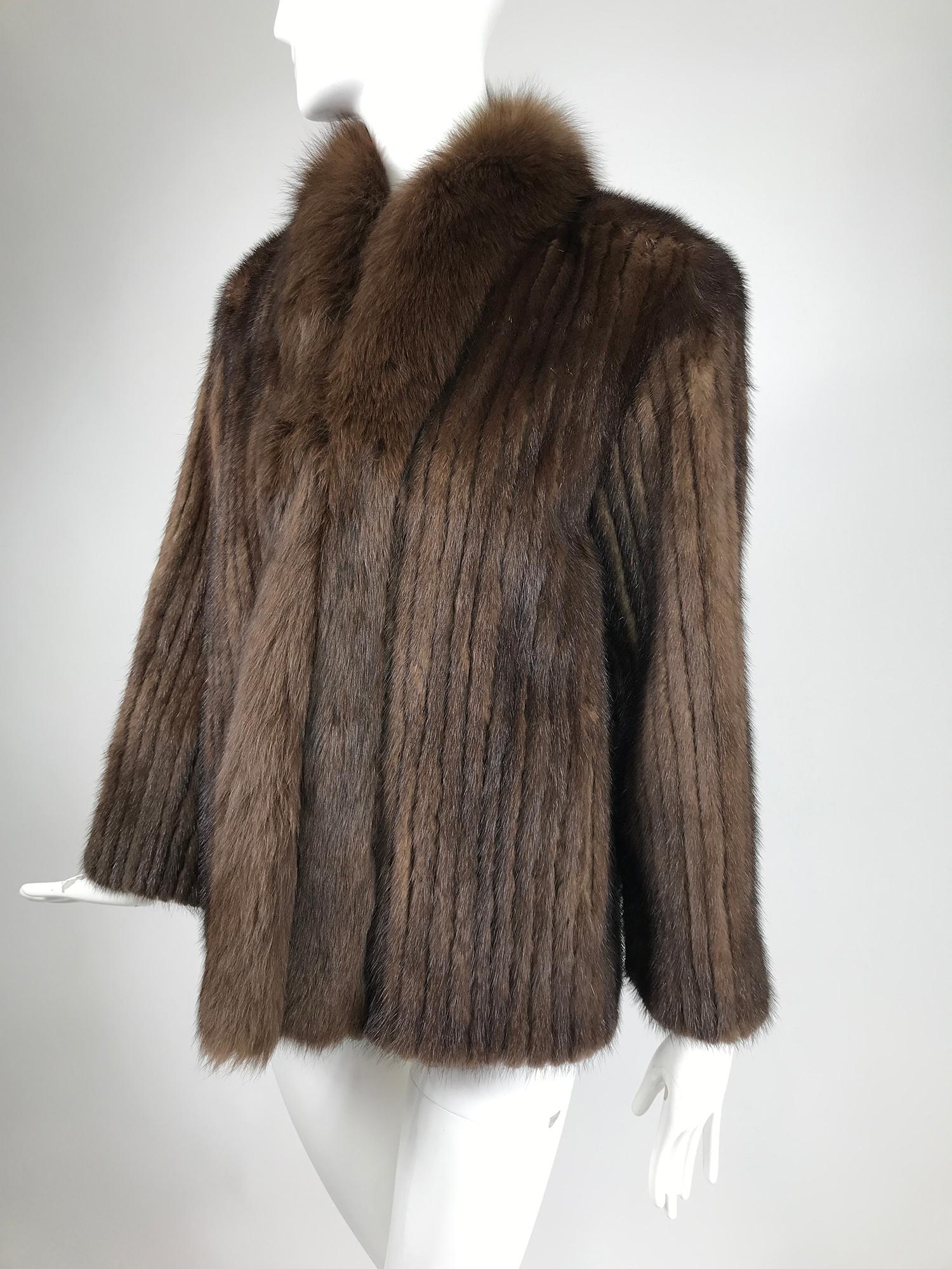 SAGA chestnut mink jacket with fox fur collar and front facings. Made in Denmark. This beautiful jacket is hip length with on seam front pockets. The fur is done in narrow vertical strips, reminiscent of wide wale corduroy. Closes at the front with