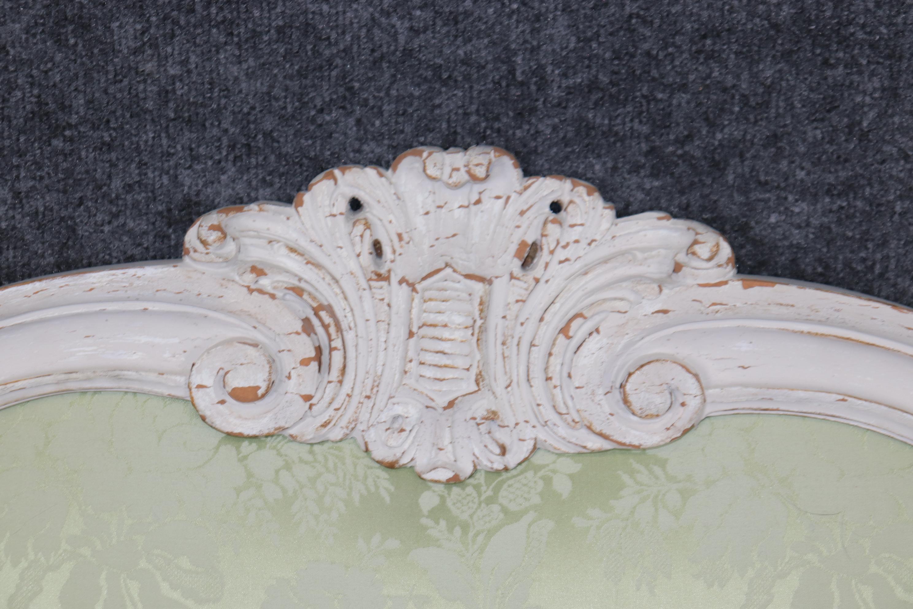 Il s'agit d'une magnifique tête de lit de style Louis XV, peinte en blanc et vieillie, tapissée de damas vert sauge (peut-être de la soie). La tête de lit est en très bon état avec une peinture blanche craquelée et un très beau dossier tapissé. La