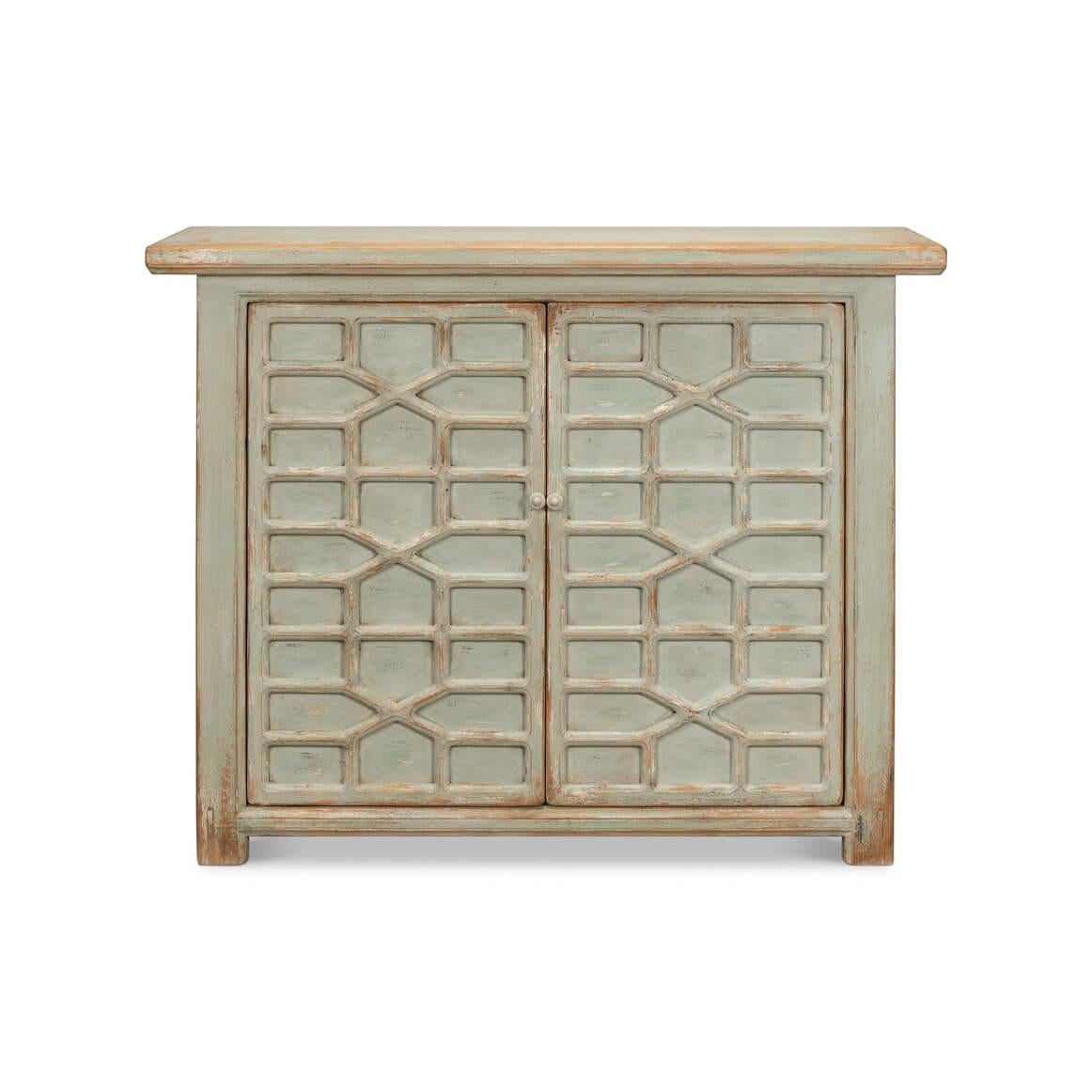 A charming cabinet, beautifully crafted with a distressed painted finish on pine, evoking a lived-in look rich with stories. The blind fretwork door panels feature a lattice pattern reminiscent of old-world craftsmanship.

Behind the two cupboard