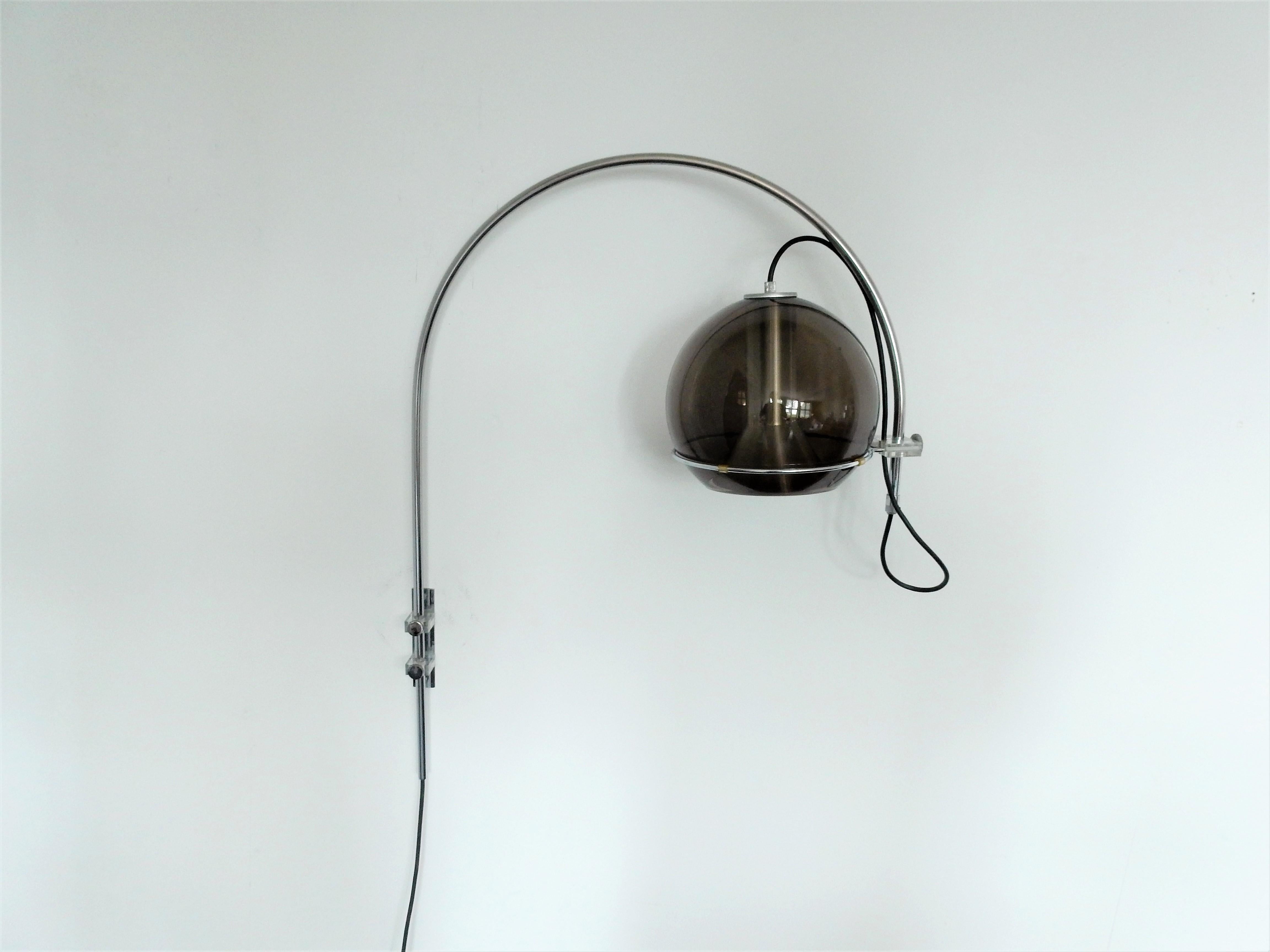 This elegant globe wall lamp, model Sagittarius' was designed by Frank Ligtelijn for Raak Amsterdam. A chrome-plated arch that is swivable sideways and adjustable in height. Mounted to the wall, with the classical smoked glass globe and aluminum