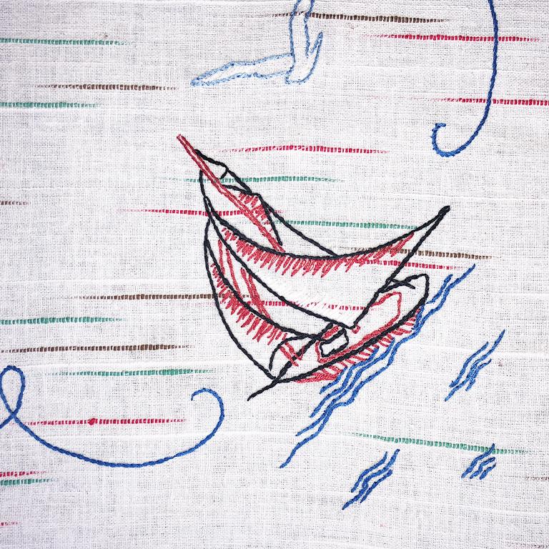Rectangle nautical theme table cloth. Featuring a cream background and nautical scenes handstitched into the sides. Images of sailboats, birds, anchors, and lifesavers. Green, red, black and blue ikat pattern stitched throughout. Would be a great