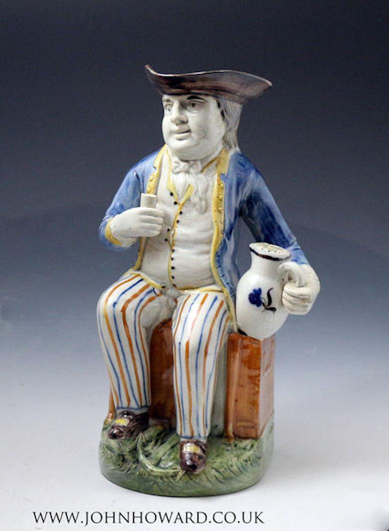 Prattware pottery Toby Jug known as the Sailor. The well-attired figure has exceptional quality decorations in the Prattware color palette. He is shown seated on a chest with a benign smile holding a beaker and frothing jug of ale. The base of the