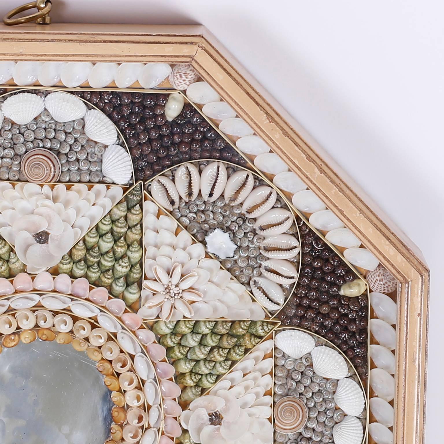 Sailors valentine composed in precise geometric patterns using an impressive array of petite seashell specimens with a centre mirror. Presented in an octagon shaped shadow box.